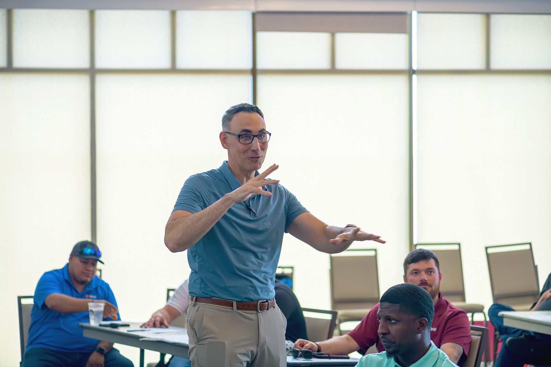 A man is giving a presentation to a group of people in a classroom.