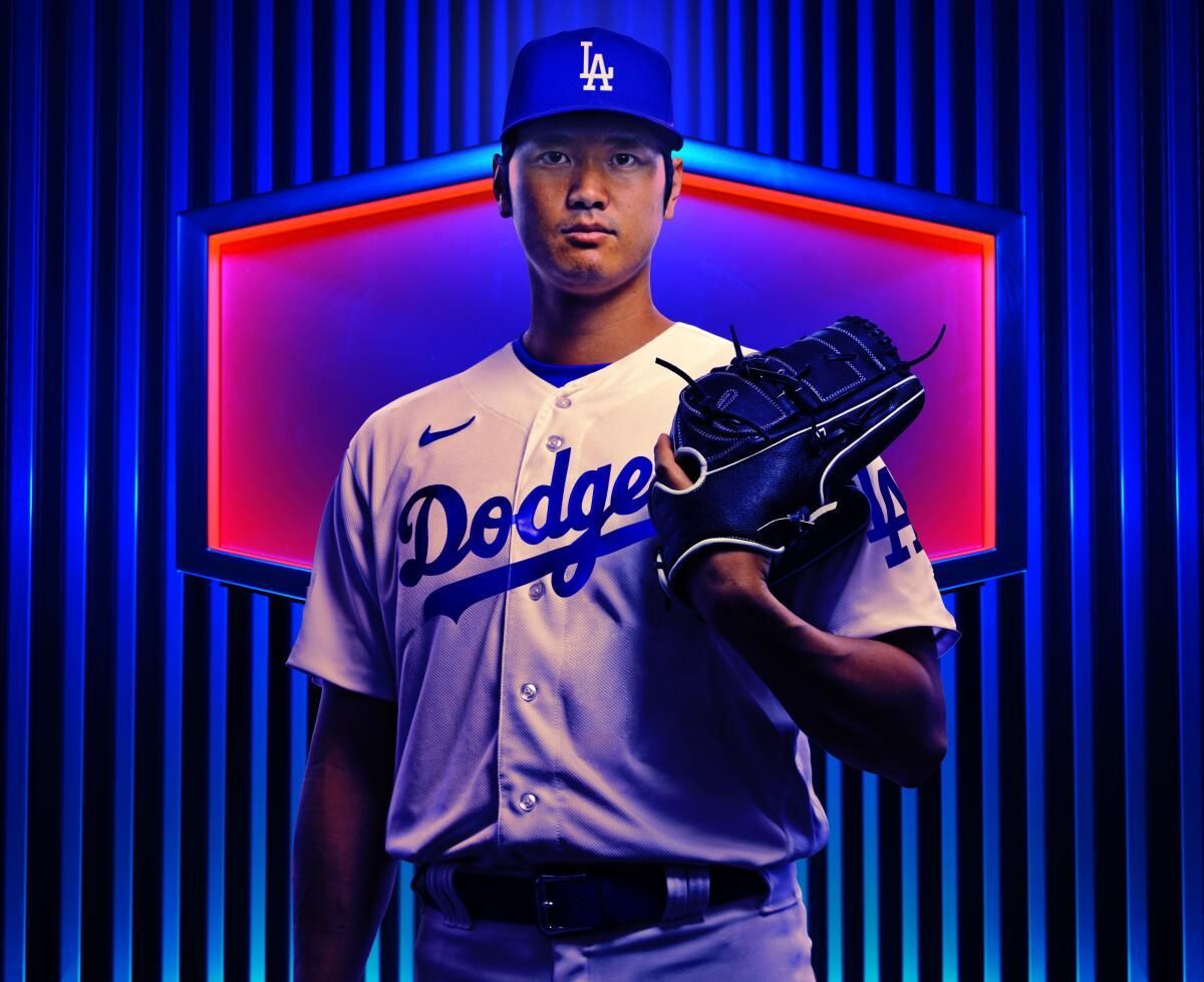 A baseball player is wearing a dodgers uniform and holding a glove.