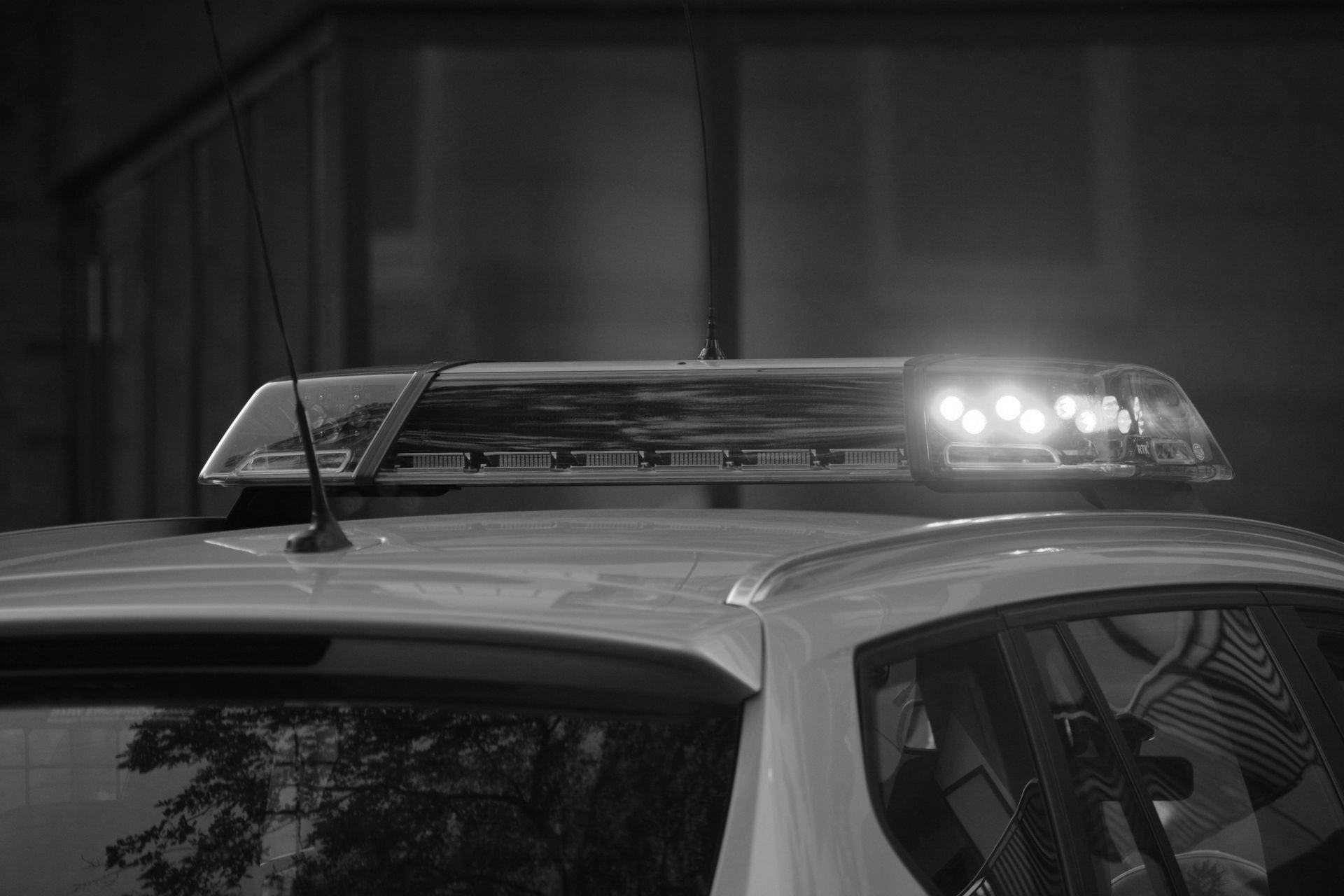 A black and white photo of a police car with a light on top of it.