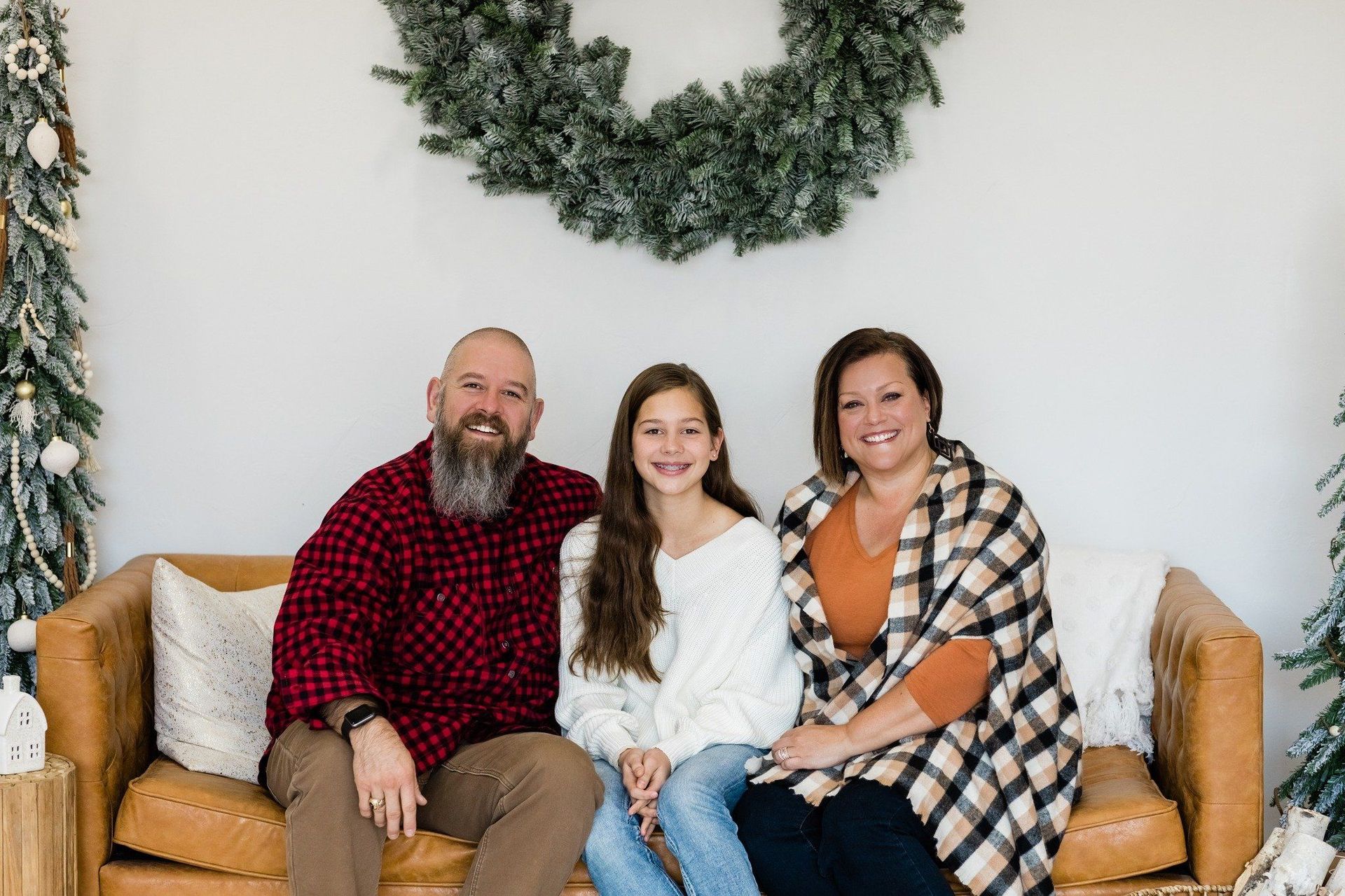 A family is posing for a picture while sitting on a couch.