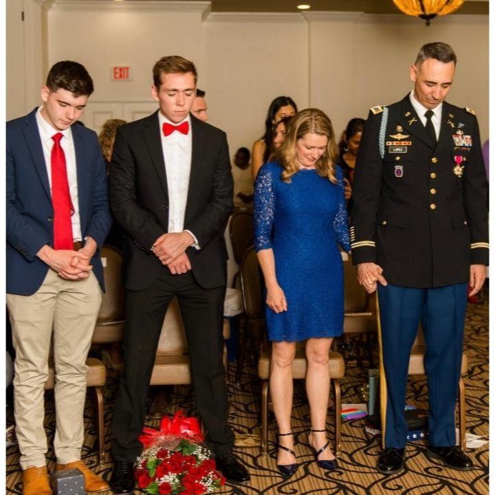 A man in a military uniform stands next to a woman in a blue dress