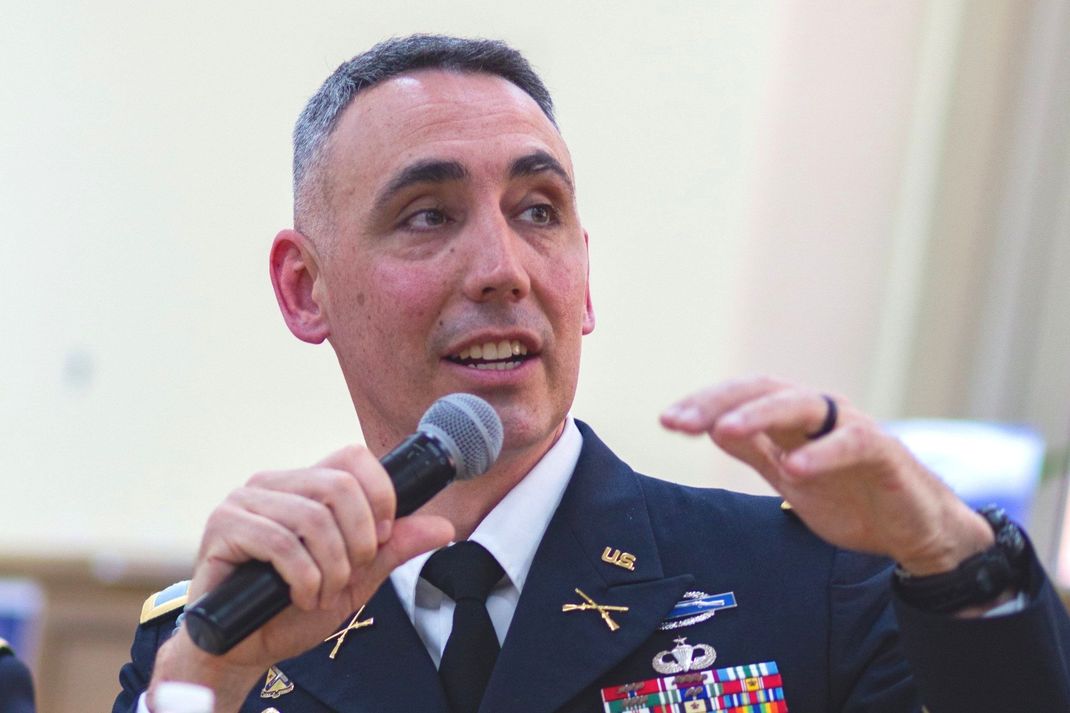 A man in a military uniform is holding a microphone