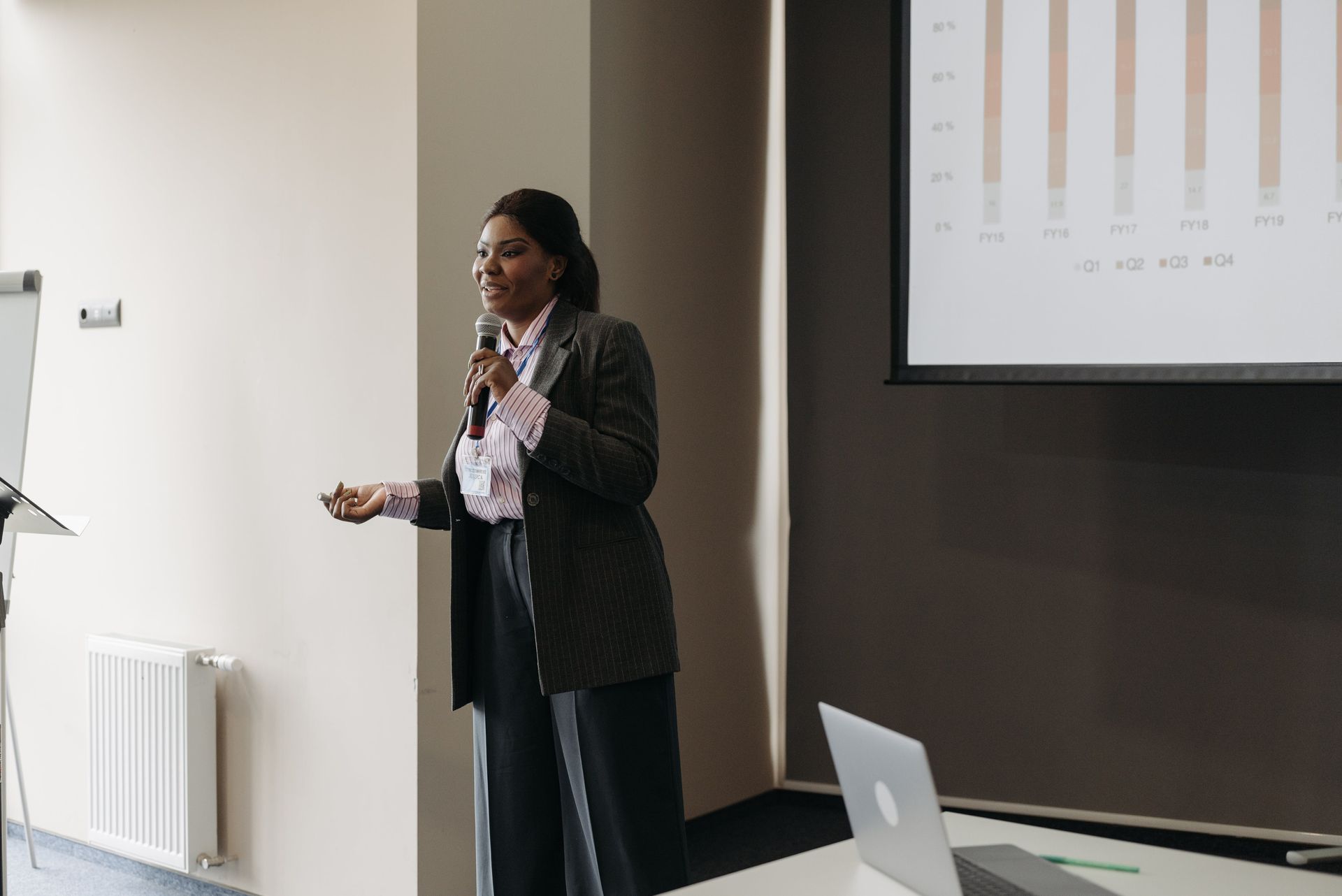 A woman is giving a presentation in front of a projector screen.