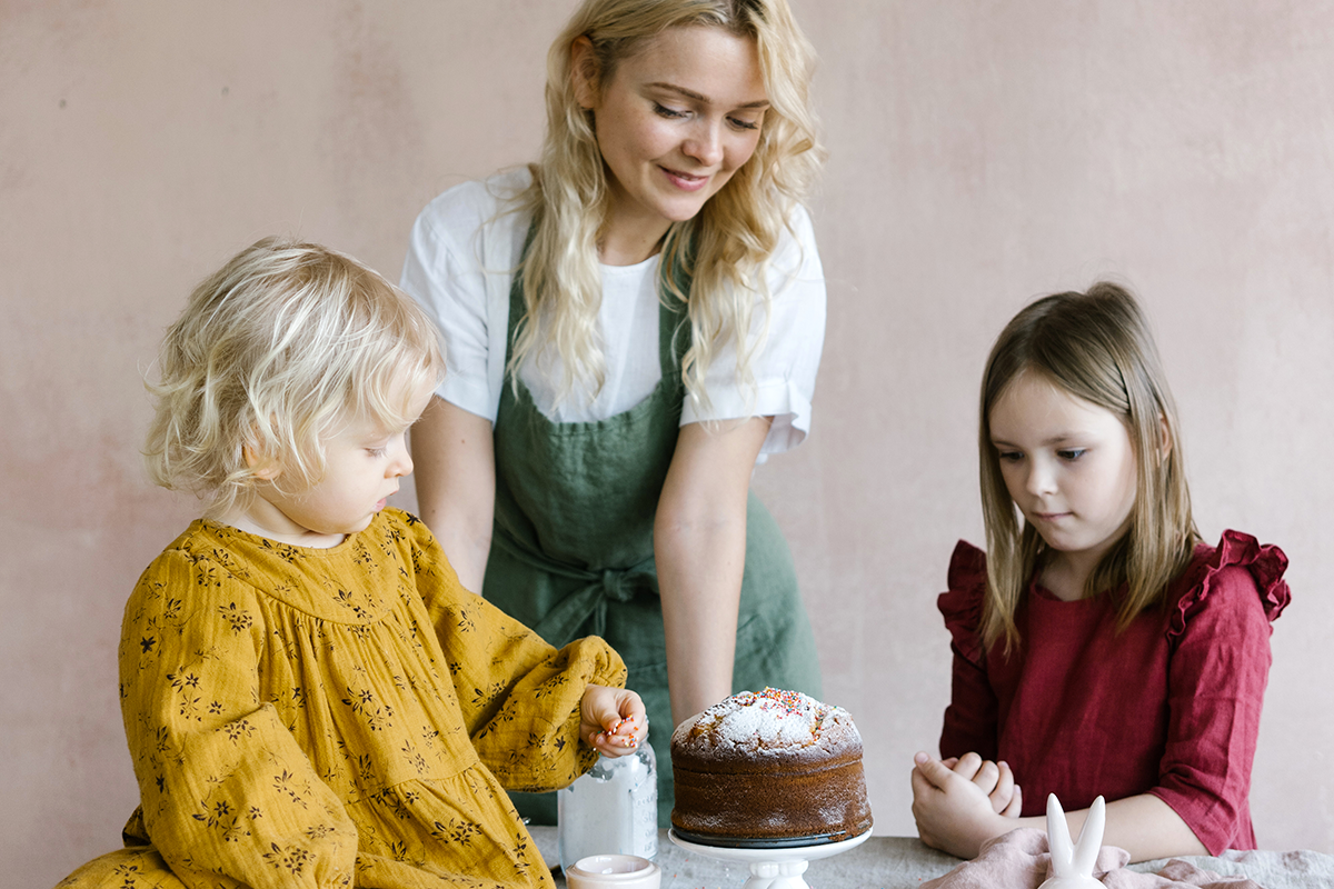 mother with daughters looking at a cake