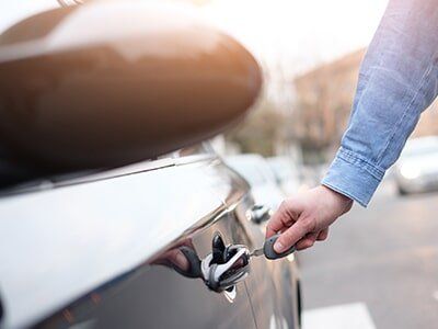 Hand holding a car key and opening the car door — Car Rentals in Lantana, FL