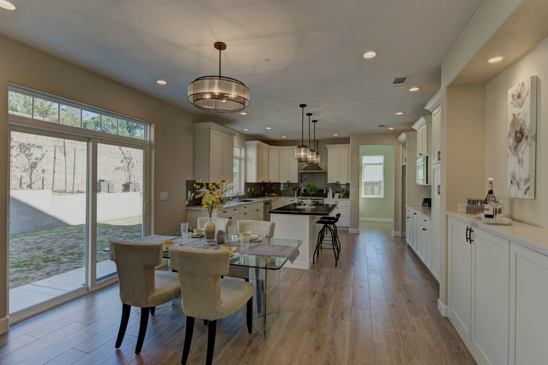 A dining room with a table and chairs and a kitchen with sliding glass doors.