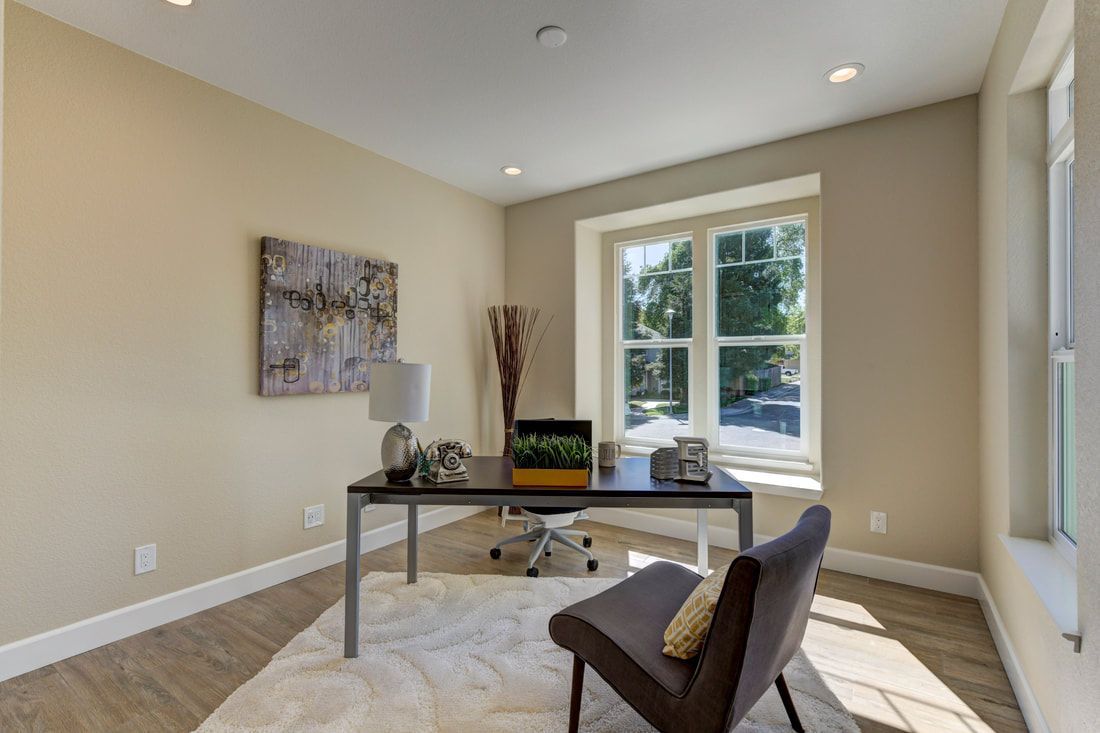 A home office with a desk , chair , lamp and window.