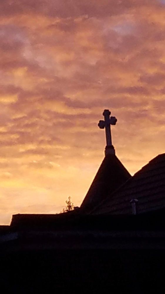 A cross on top of a building at sunset