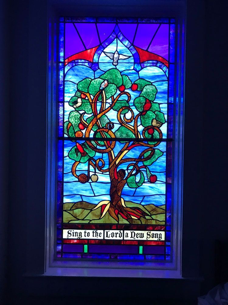 A stained glass window with a tree and a dove on it