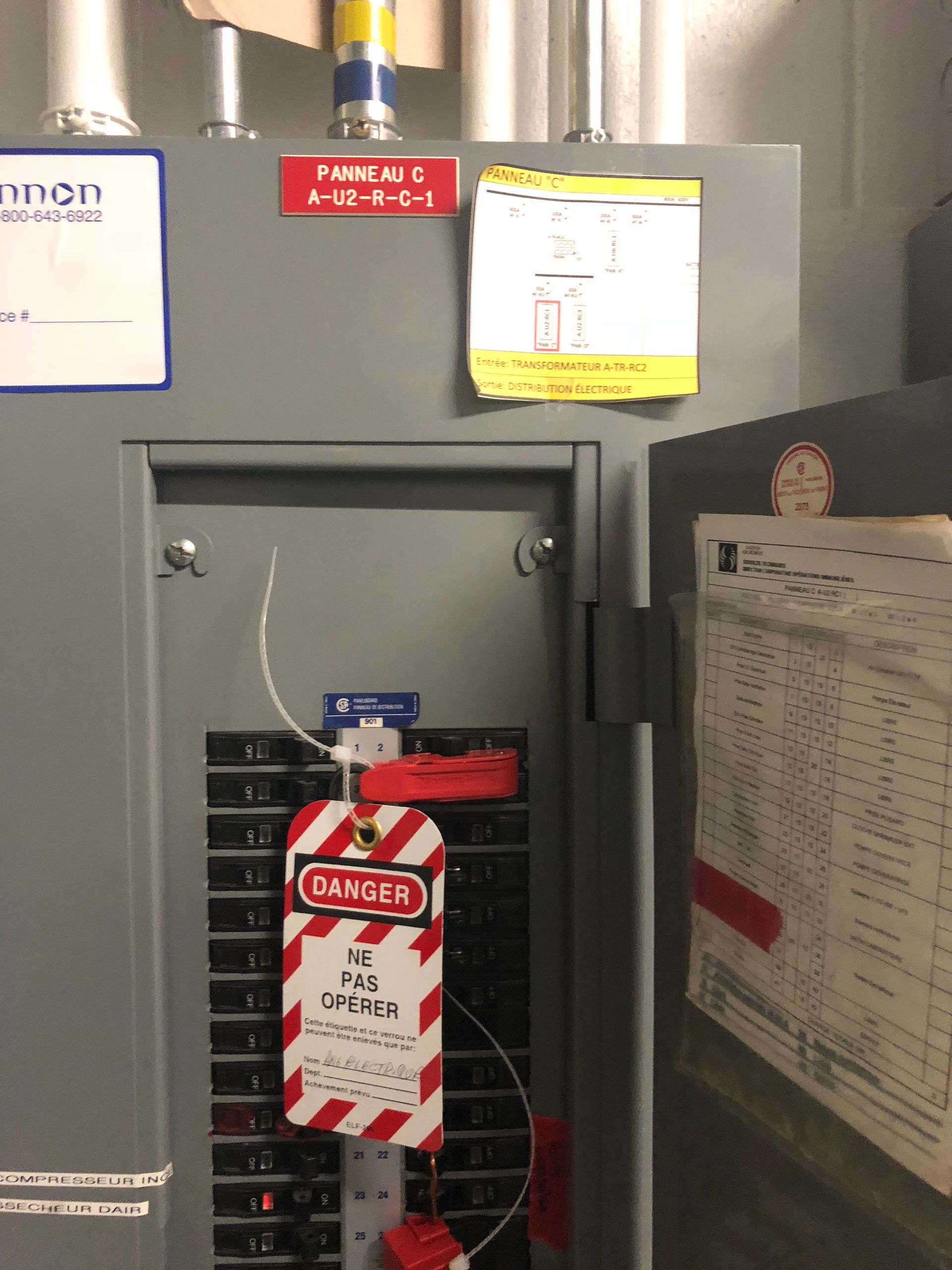 Panneau électrique verrouillé avec étiquette « DANGER », sceau rouge et diverses étiquettes.