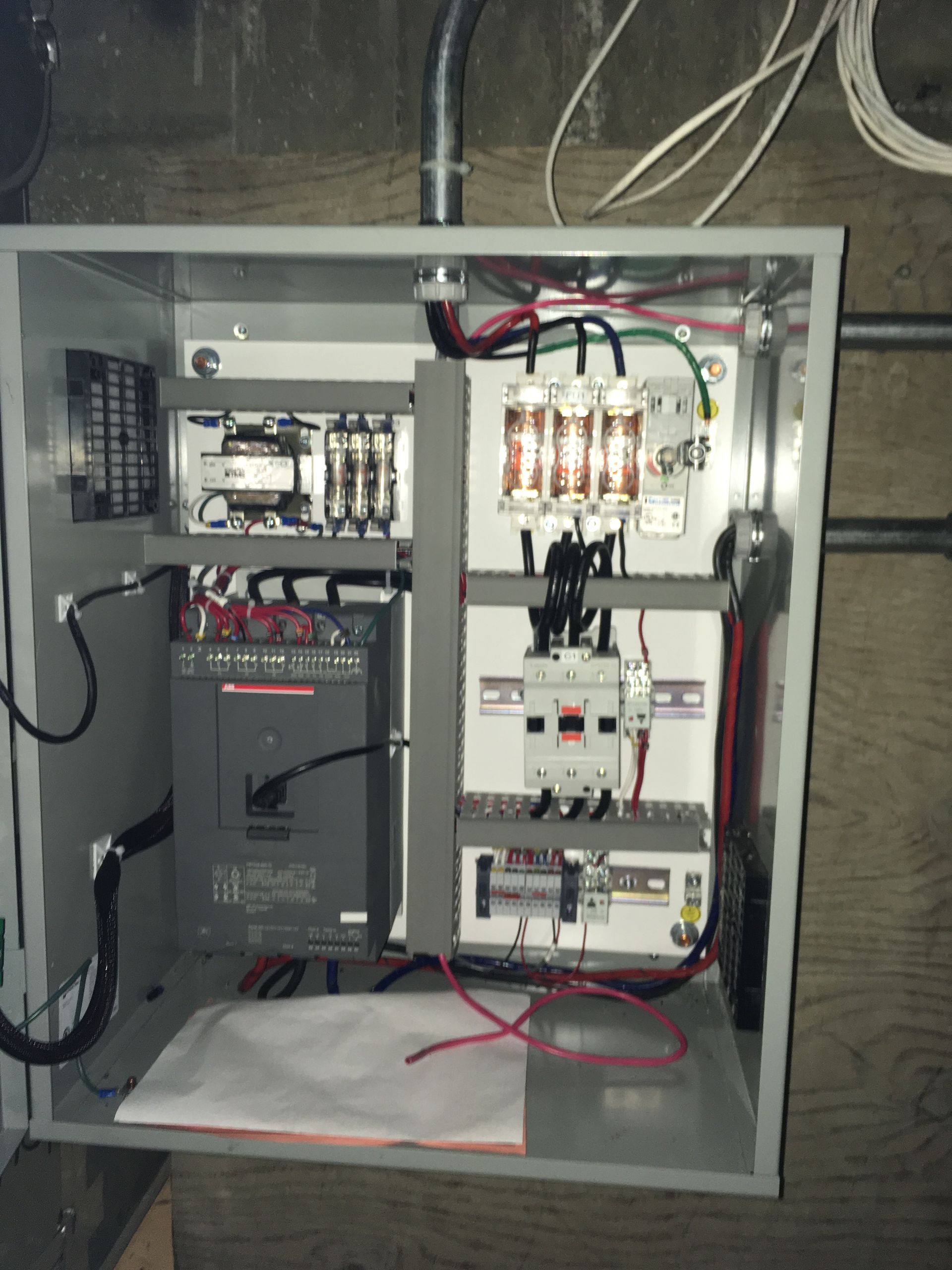 Panneau de commande électrique avec divers composants et câblage à l'intérieur d'un boîtier métallique.