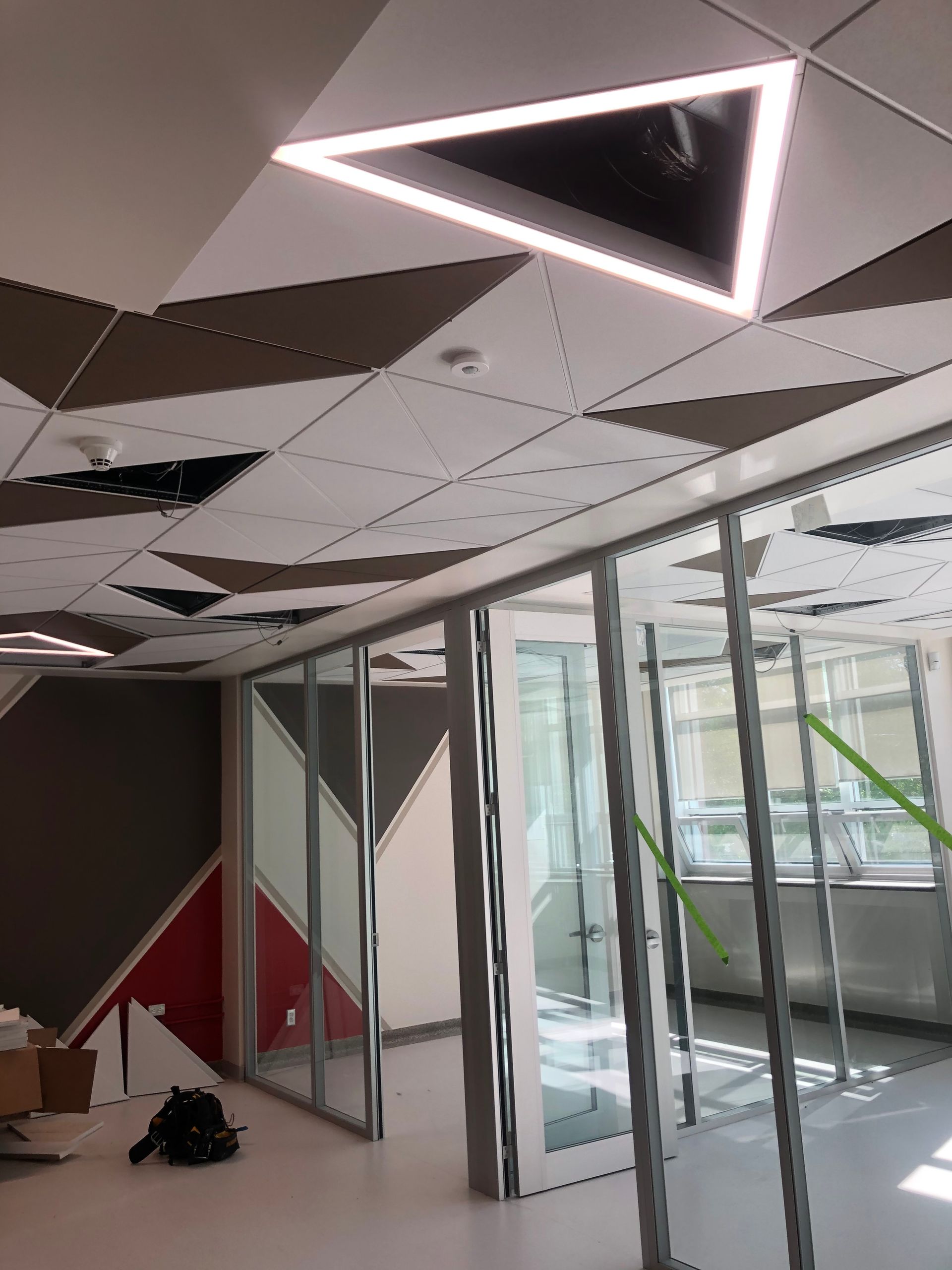 Intérieur de bureau avec un design de plafond géométrique et des murs en verre.
