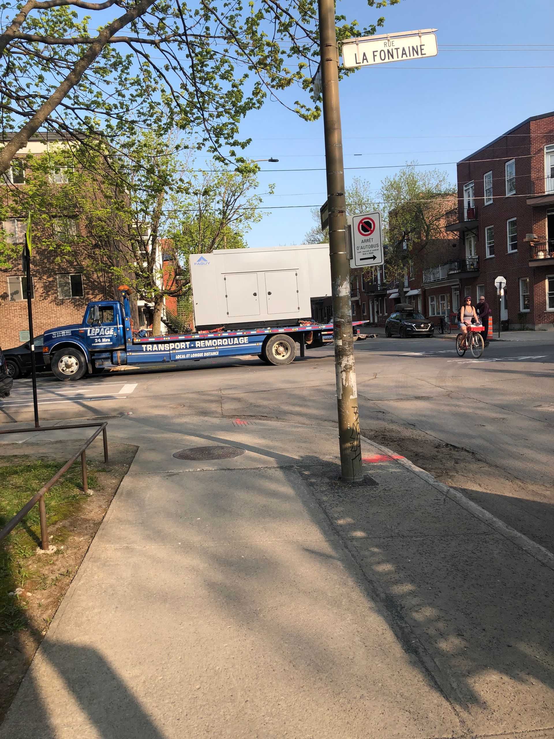 Un camion avec une grande dalle de béton au coin d'une rue ; un cycliste passe devant.