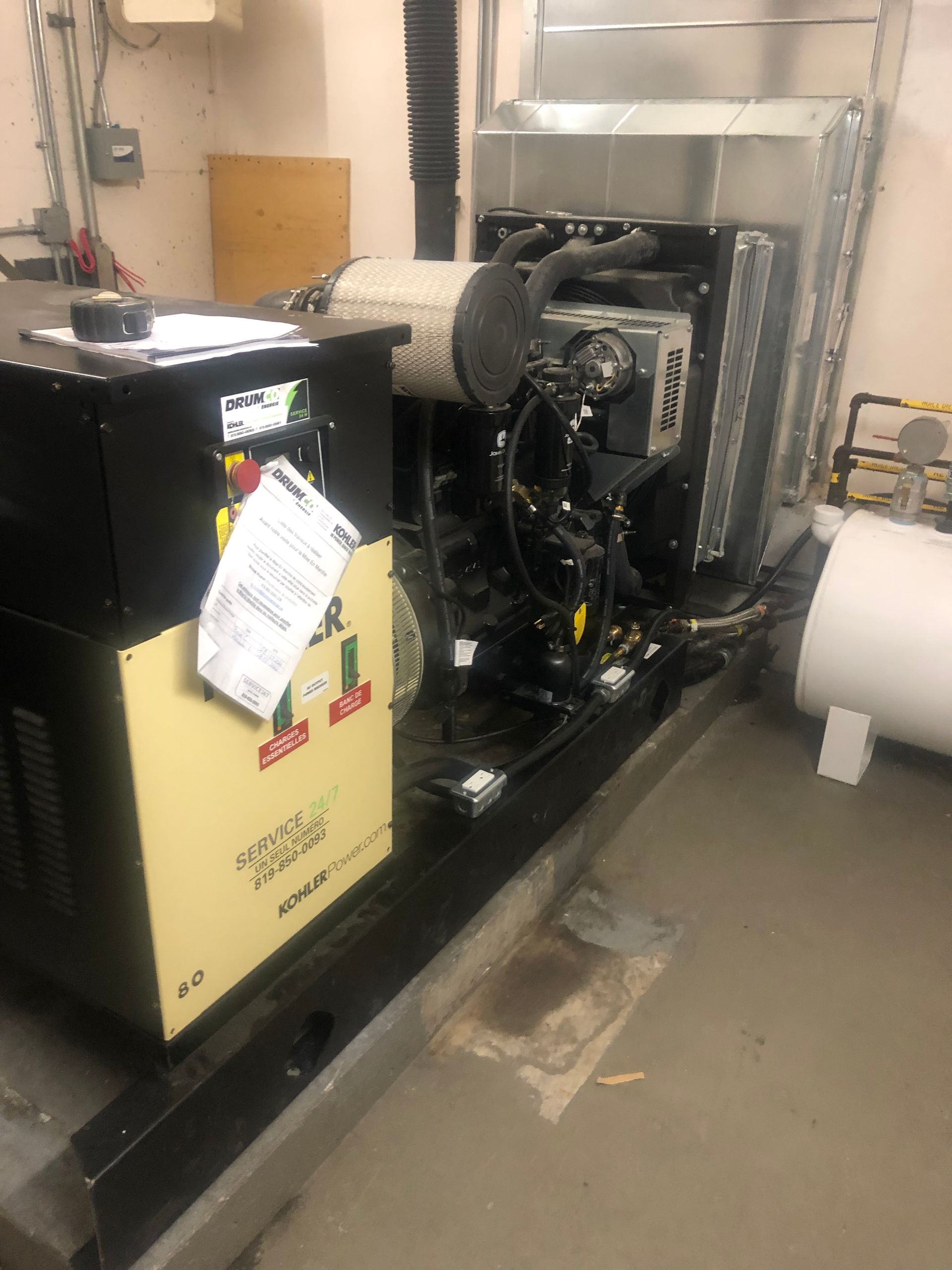 Un grand compresseur d'air industriel beige et noir avec des composants attachés dans une buanderie.