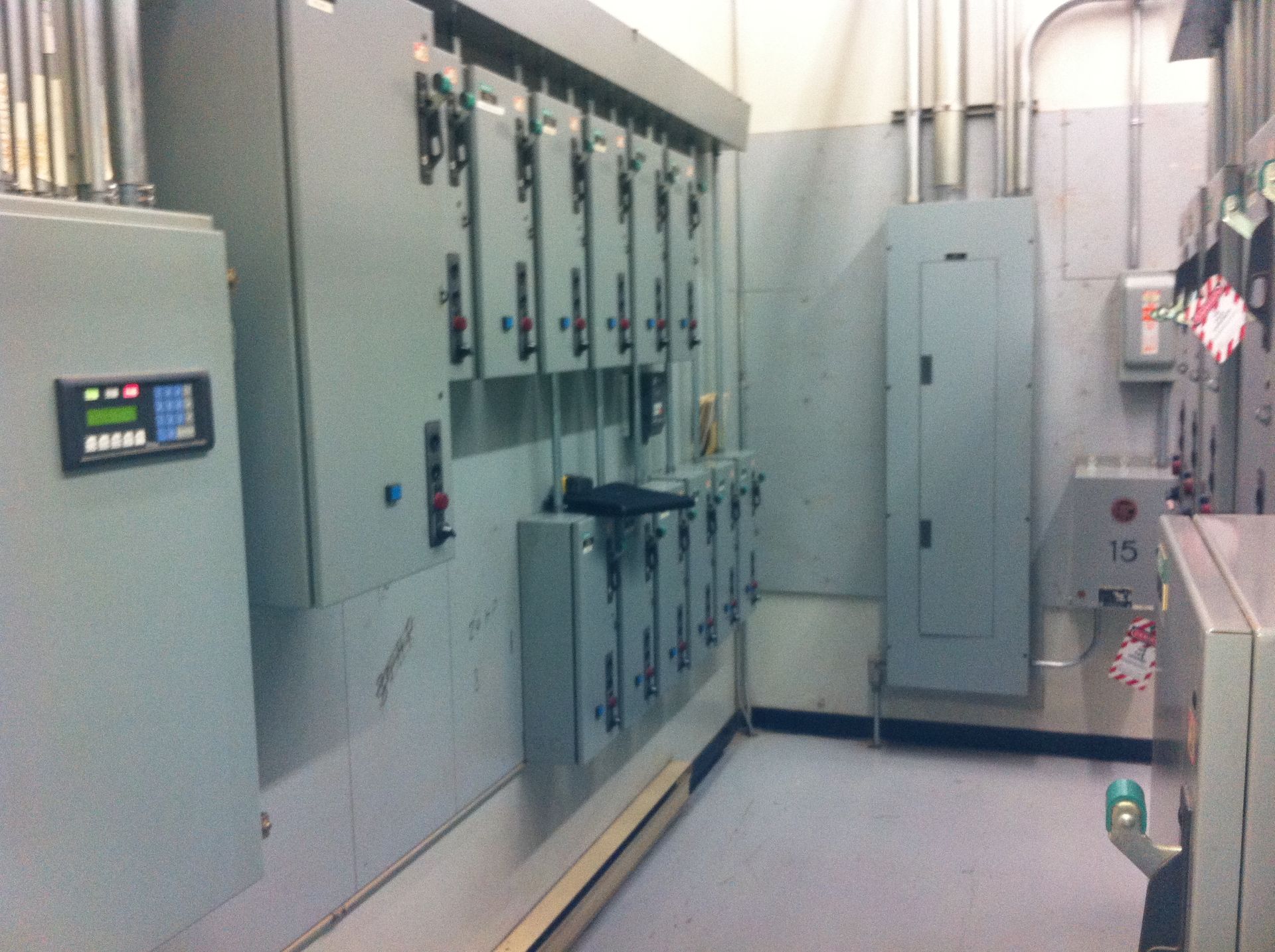 Local électrique avec panneaux gris, conduits et panneau de commande.