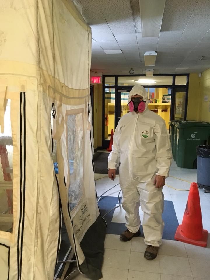 Une personne en combinaison blanche de protection se tient près d'une tente dans un couloir.