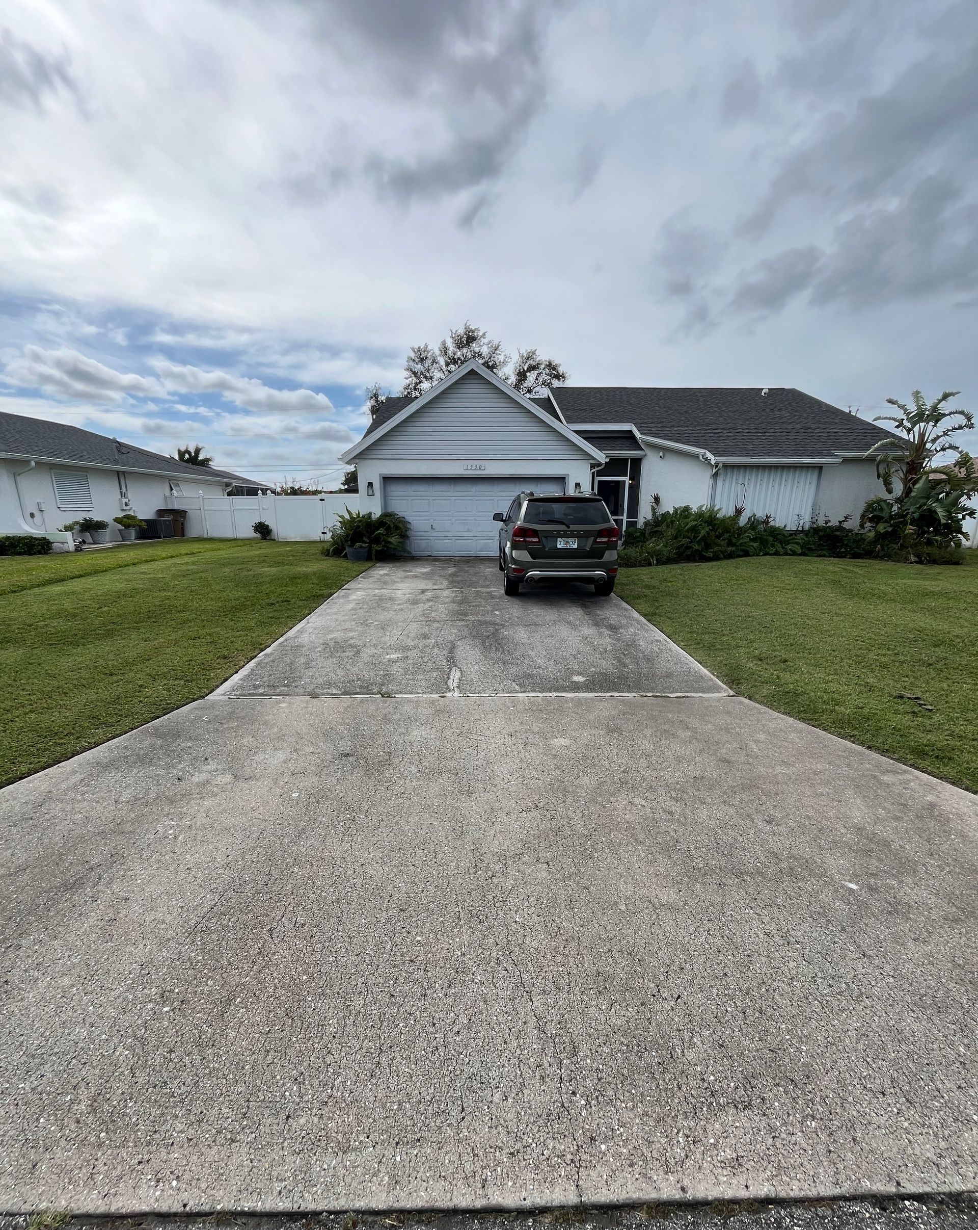 A car is parked in a driveway in front of a house.