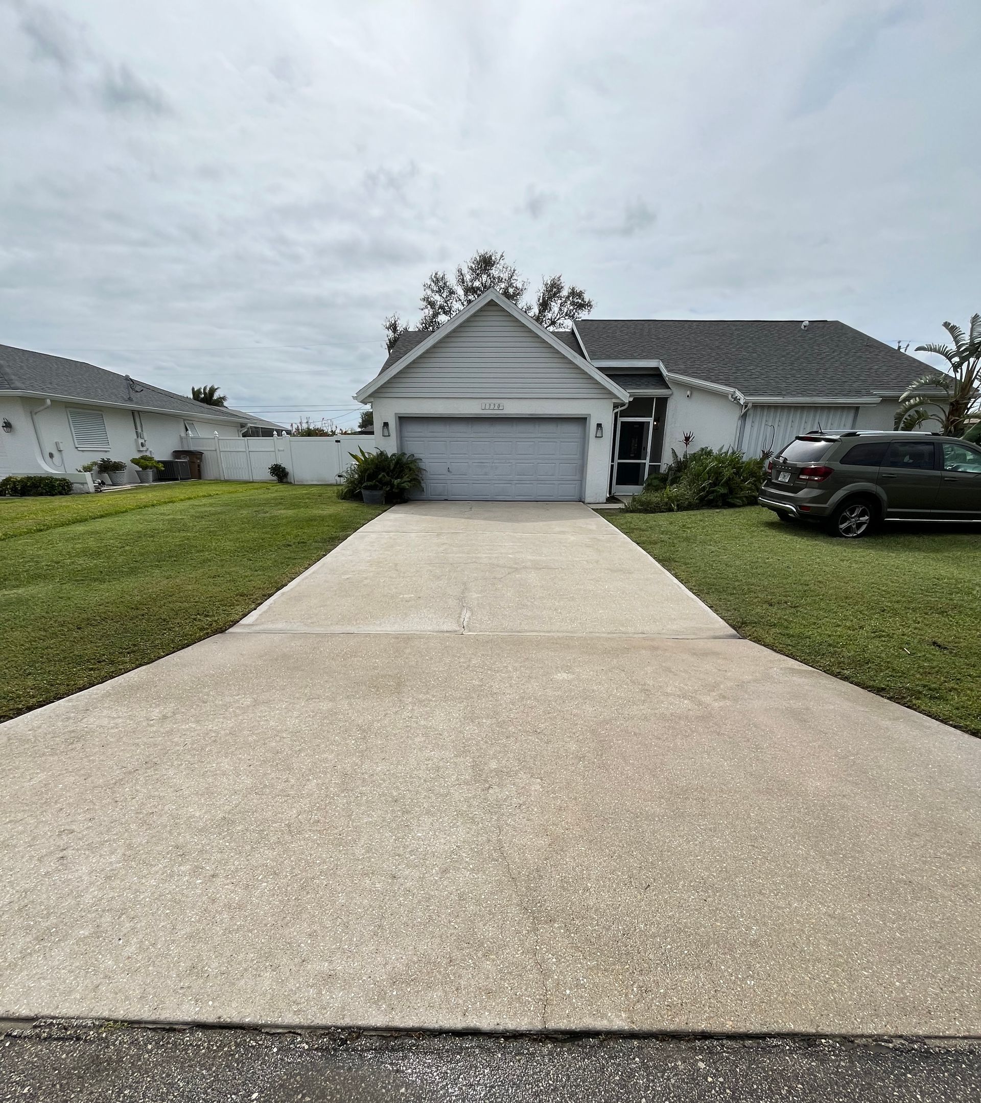 A driveway leading to a house with a car parked in front of it.