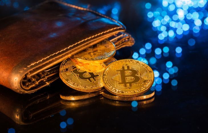 Brown wallet with Bitcoin coins spilling out, set against a blue, glowing backdrop.