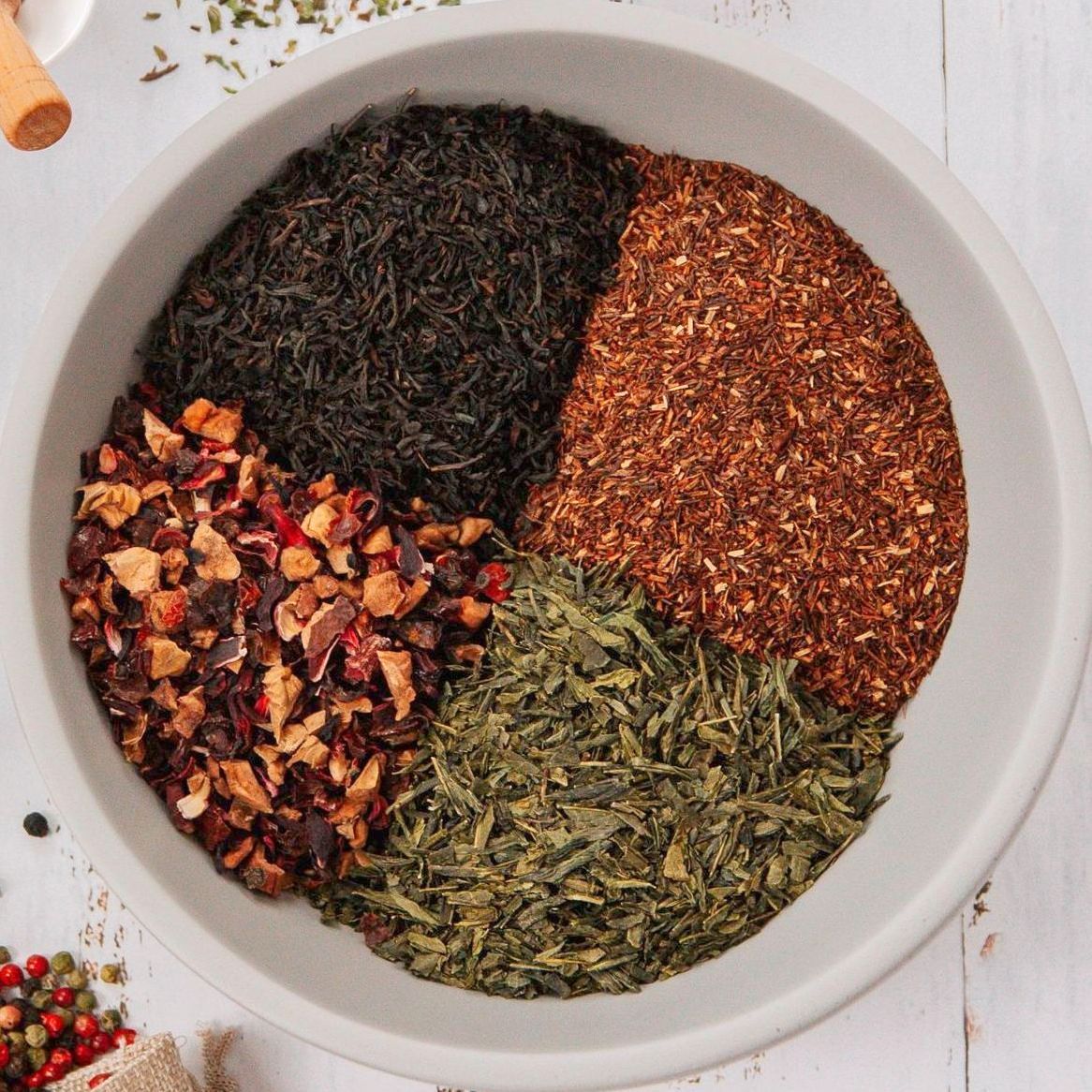eine weiße Schüssel mit verschiedenen Teesorten und Früchten