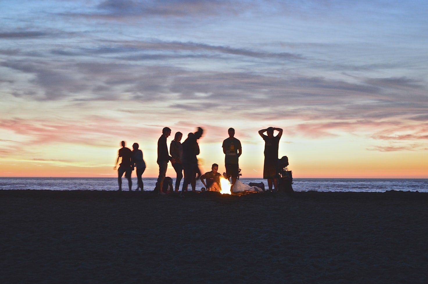 Group of friends standing around a beach bonfire at a bucks party