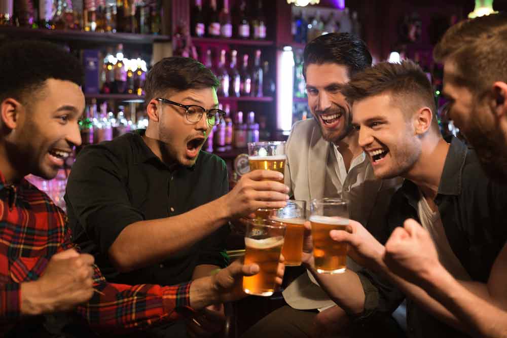Smiling male friends clinking with beer mugs