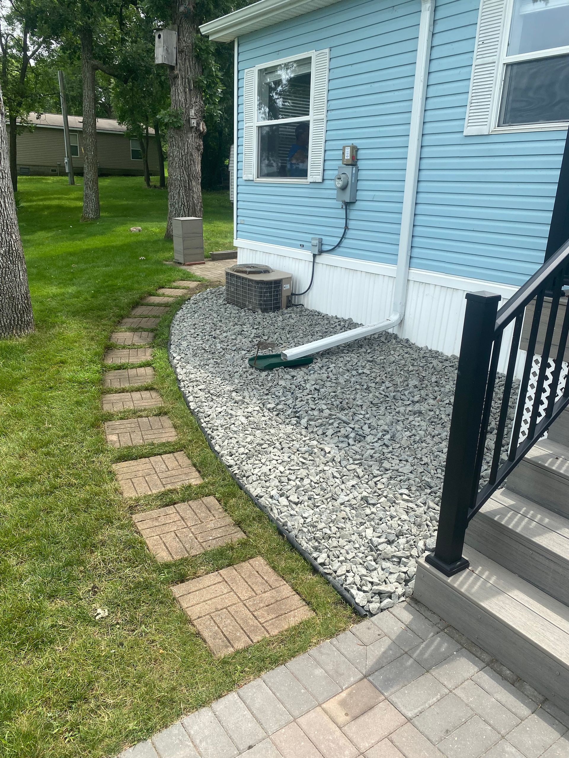 A blue house with a walkway leading to it and stairs.