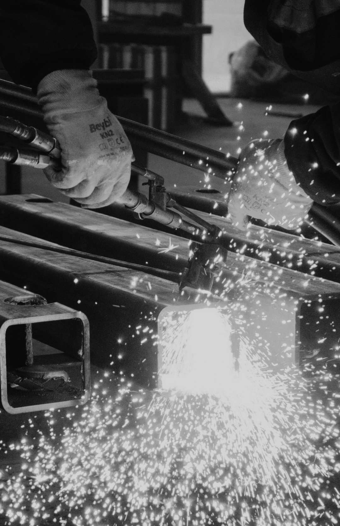 Laser cutter in action, cutting metal with sparks flying, in a workshop setting.