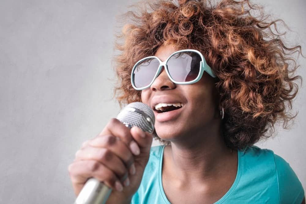 Music Instructor Virginia Beach: A woman wearing sunglasses is singing into a microphone.