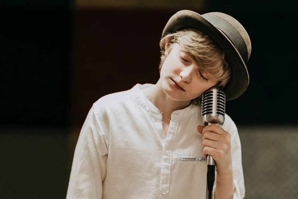 Music Instructor Virginia Beach: A young boy in a hat is singing into a microphone.