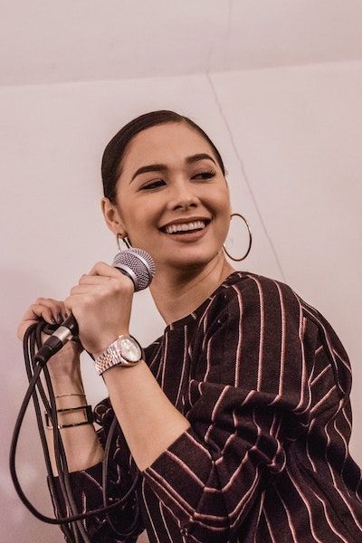 A woman in a black and red Stripe shirt sings while holding a microphone