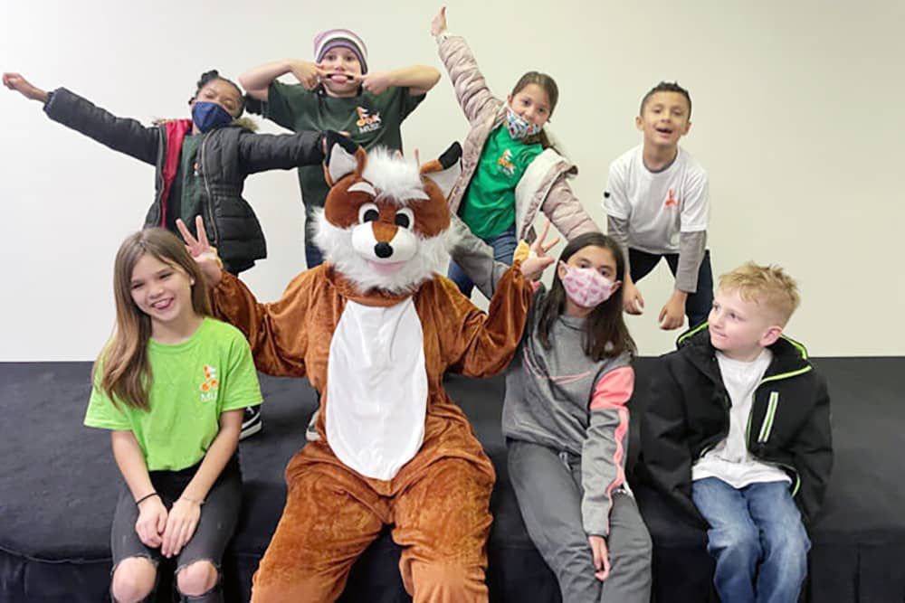 Music Lessons: A group of children are posing for a picture with a mascot in a fox costume.