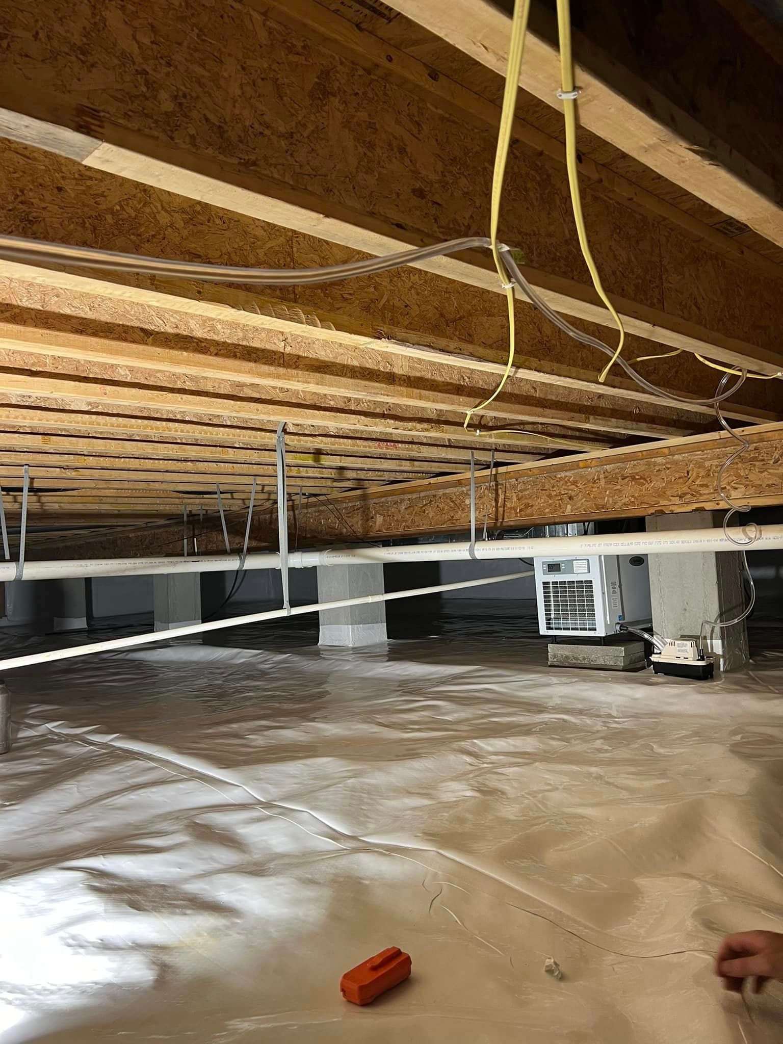 A flooded basement with wooden beams and plastic covering.