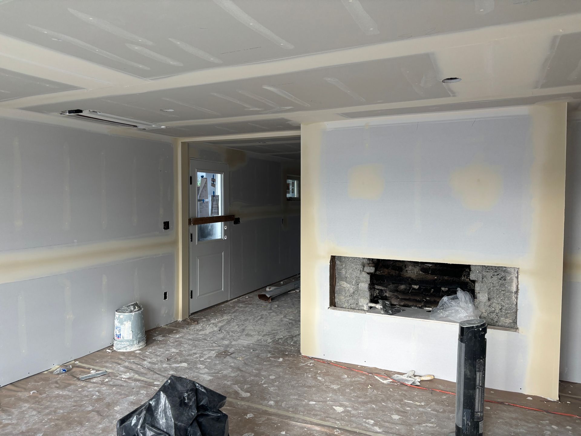 Unfinished room with drywall, a fireplace opening, and construction debris on the floor