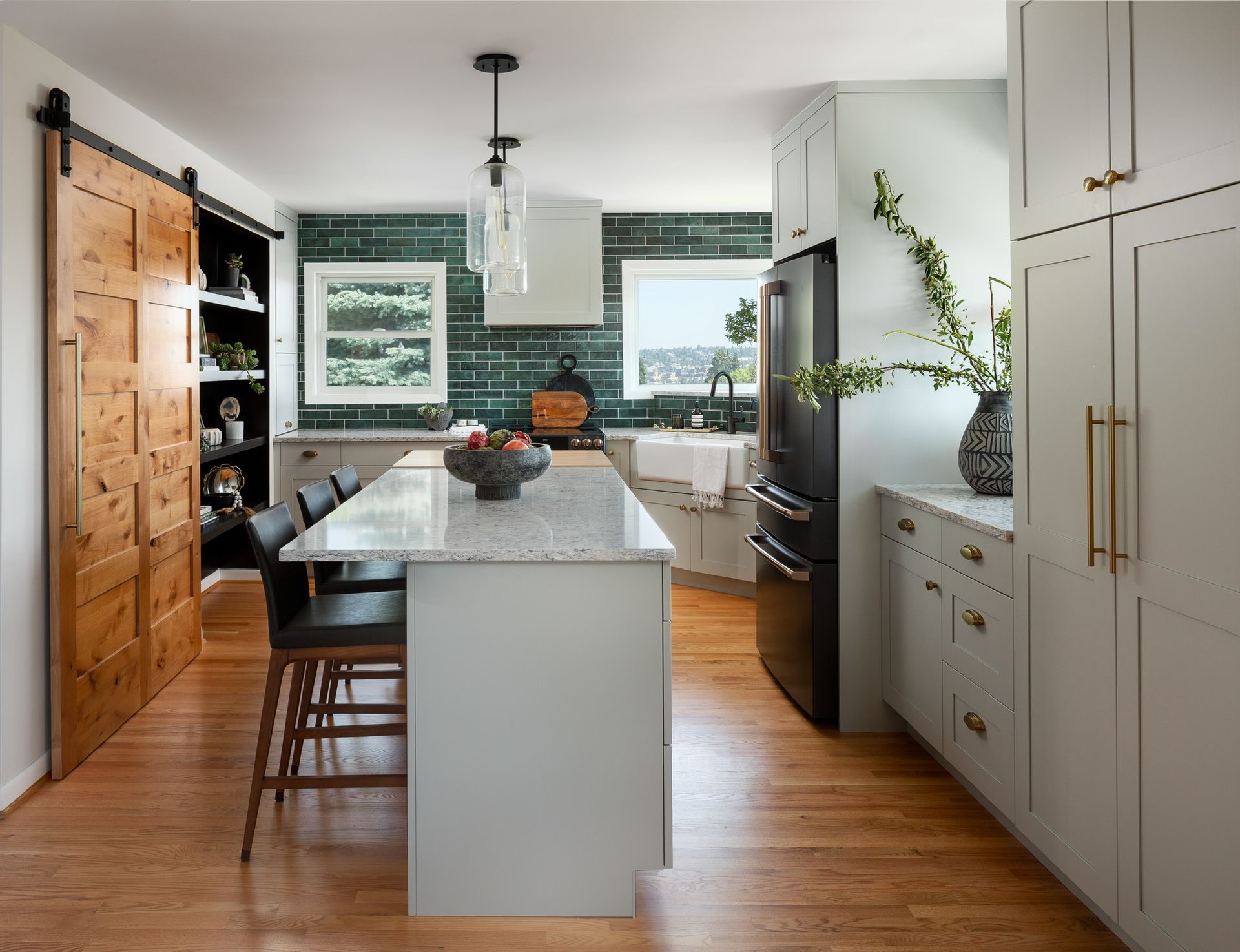 Modern kitchen with a white island, wood floors, dark tile backsplash, and large cabinet storage