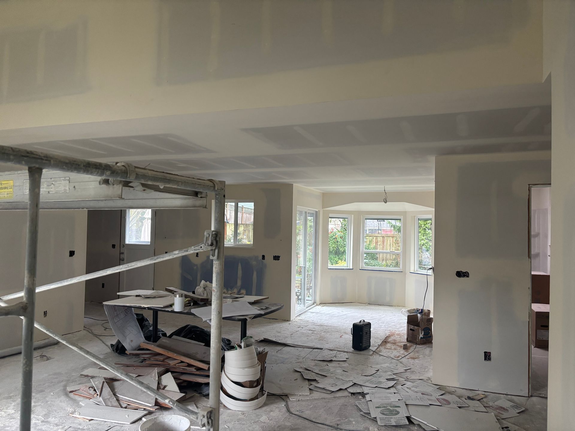 Renovation site with exposed ceiling, debris on floor, and white walls in a partially finished room