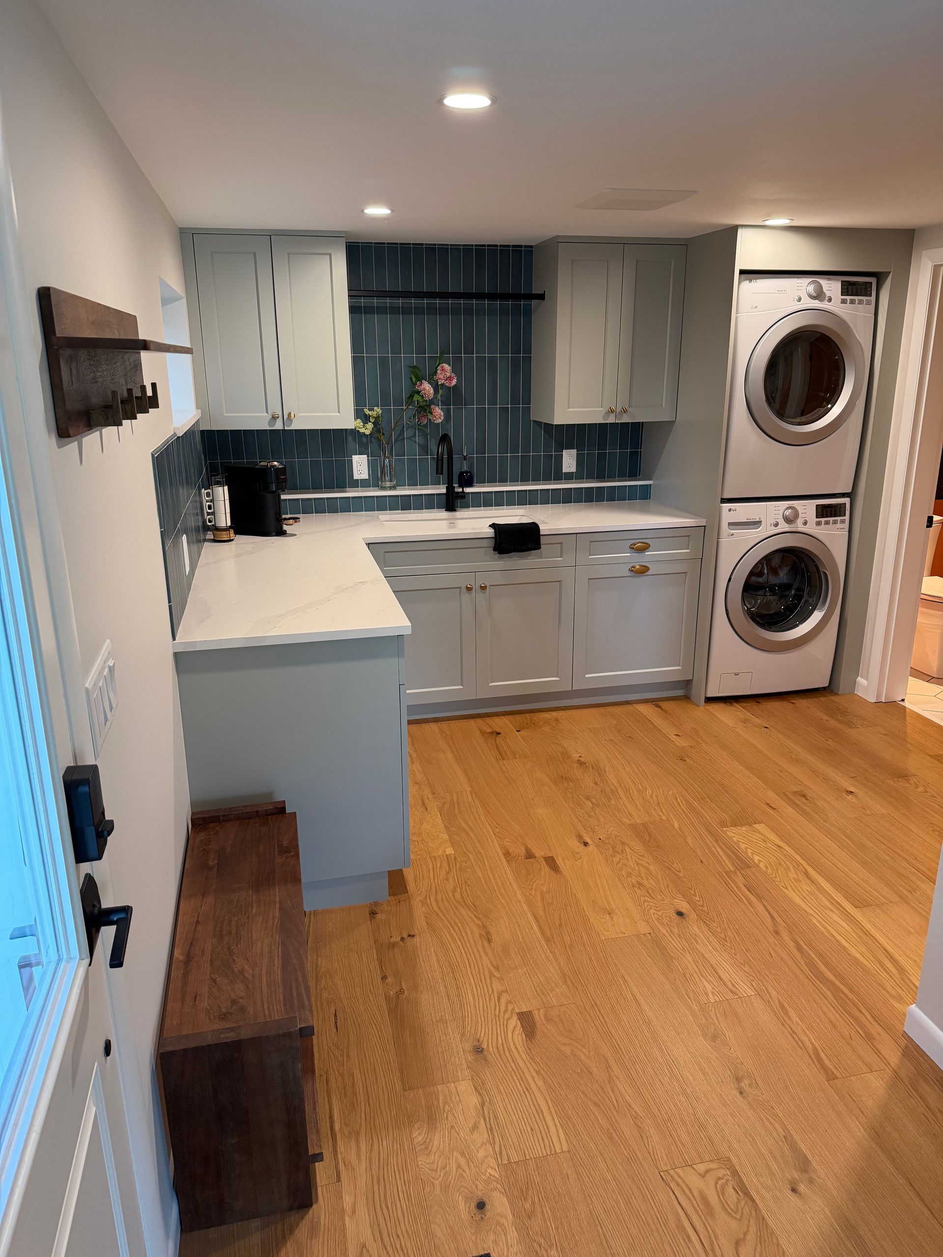 Bright kitchen with light blue cabinets, wood floor, and stacked washer and dryer by the doorway