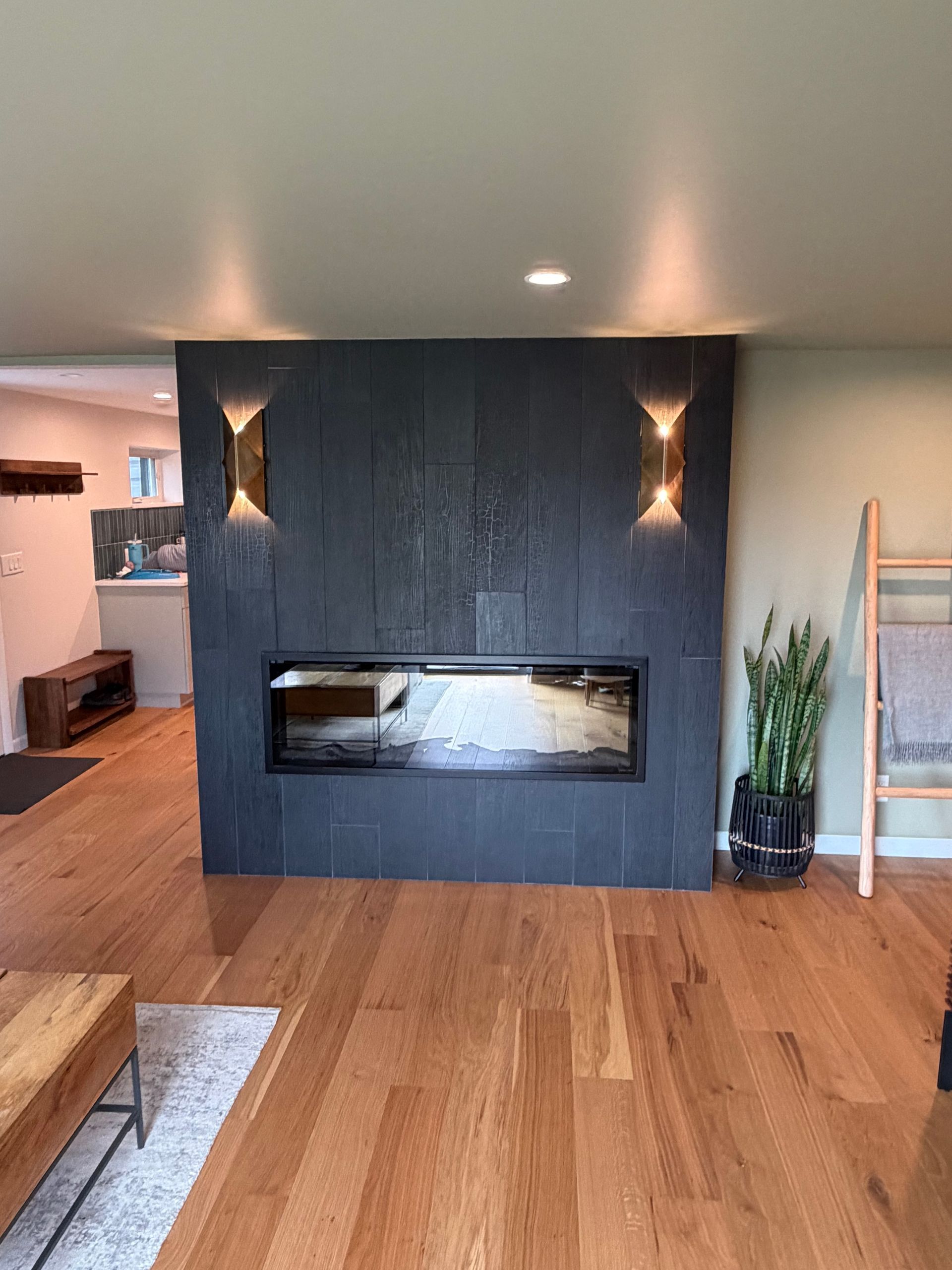 Modern living room with dark fireplace wall, hardwood floor, and built-in shelves.