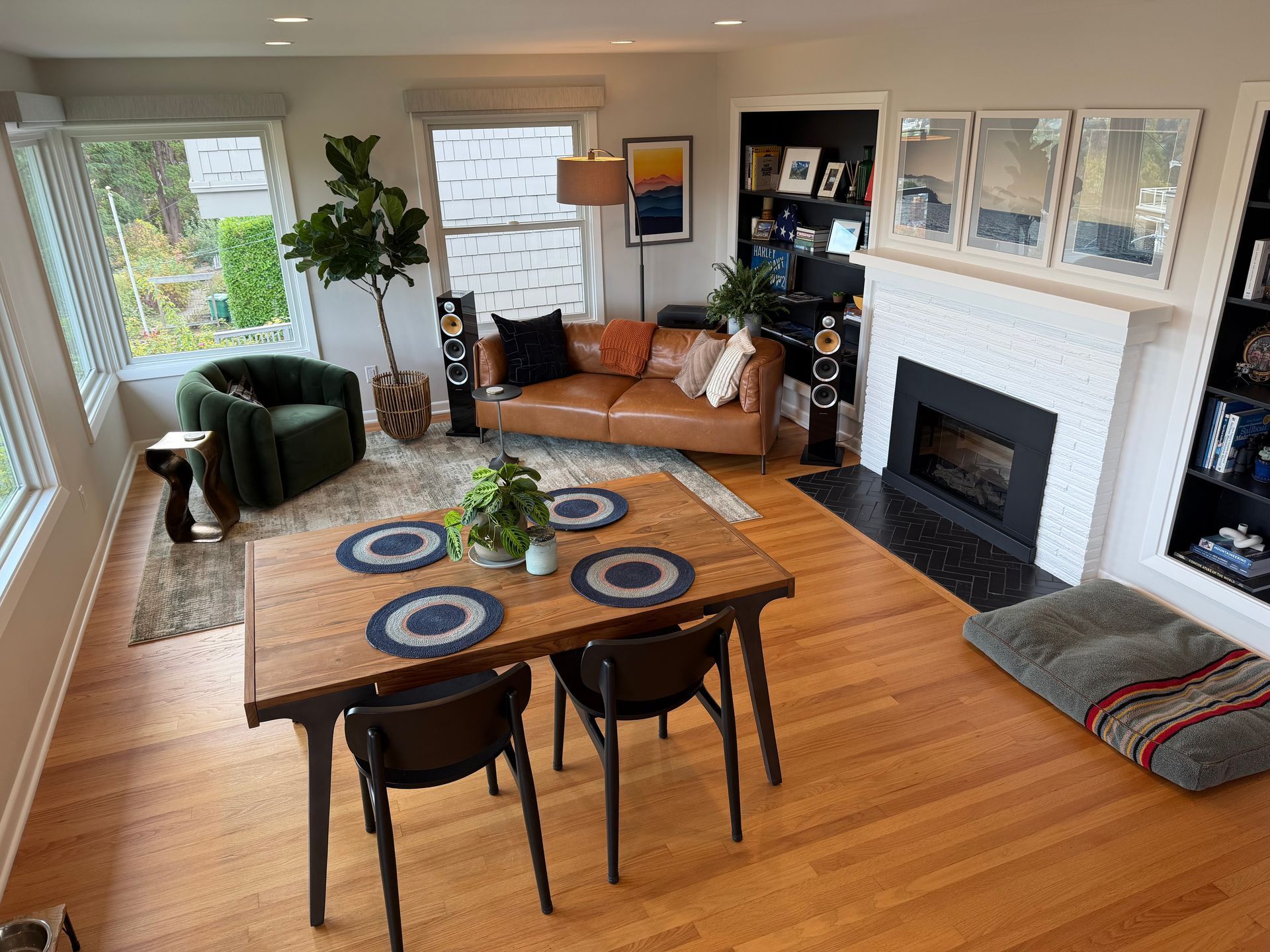 Cozy living room with fireplace, leather sofa, round dining table, and colorful rug accents