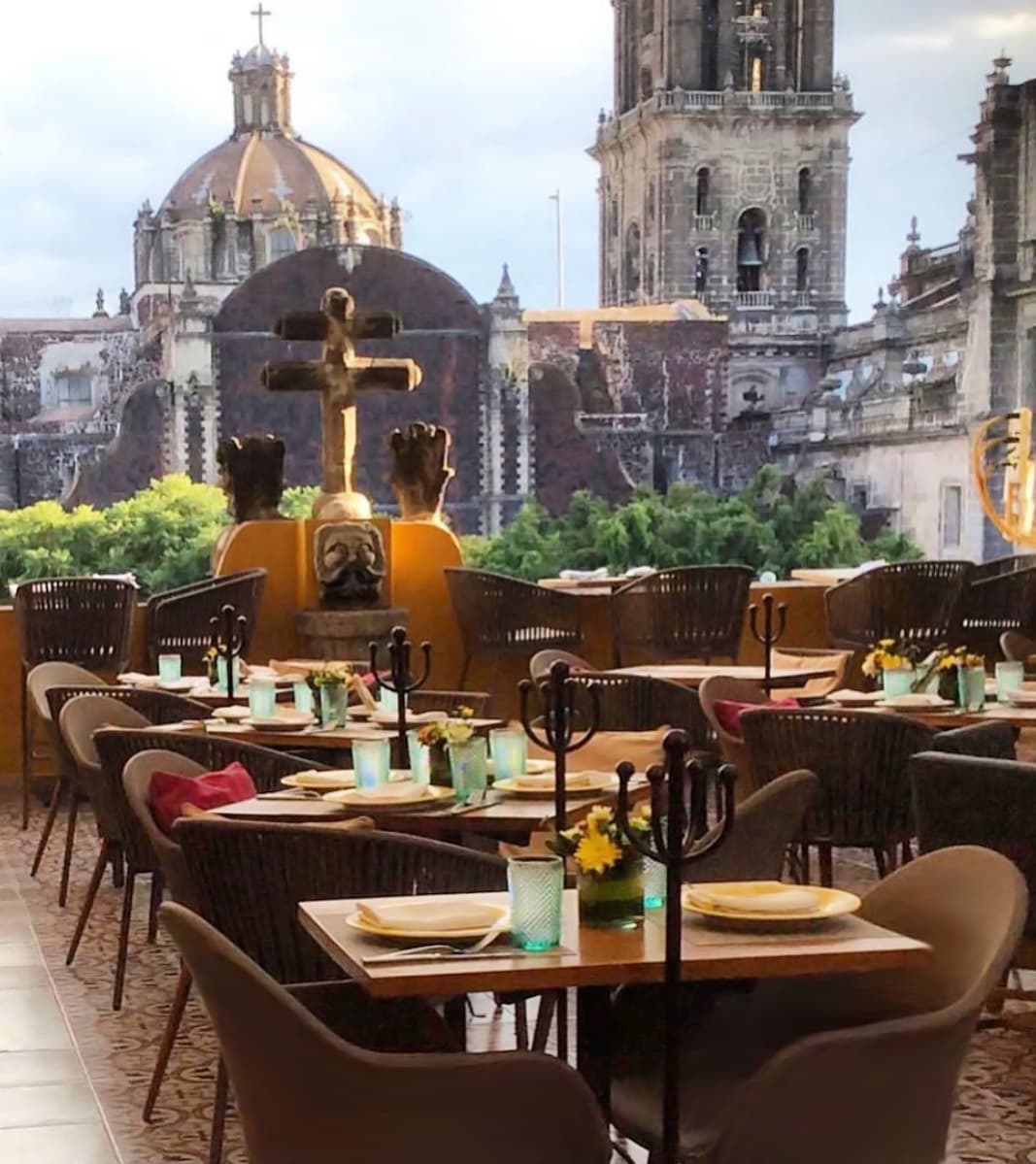 Un restaurante con mesas y sillas y una vista de una ciudad