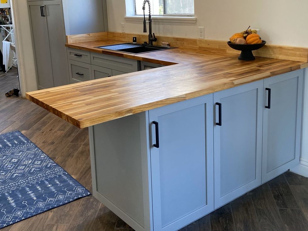 A kitchen with a wooden counter top and blue cabinets.