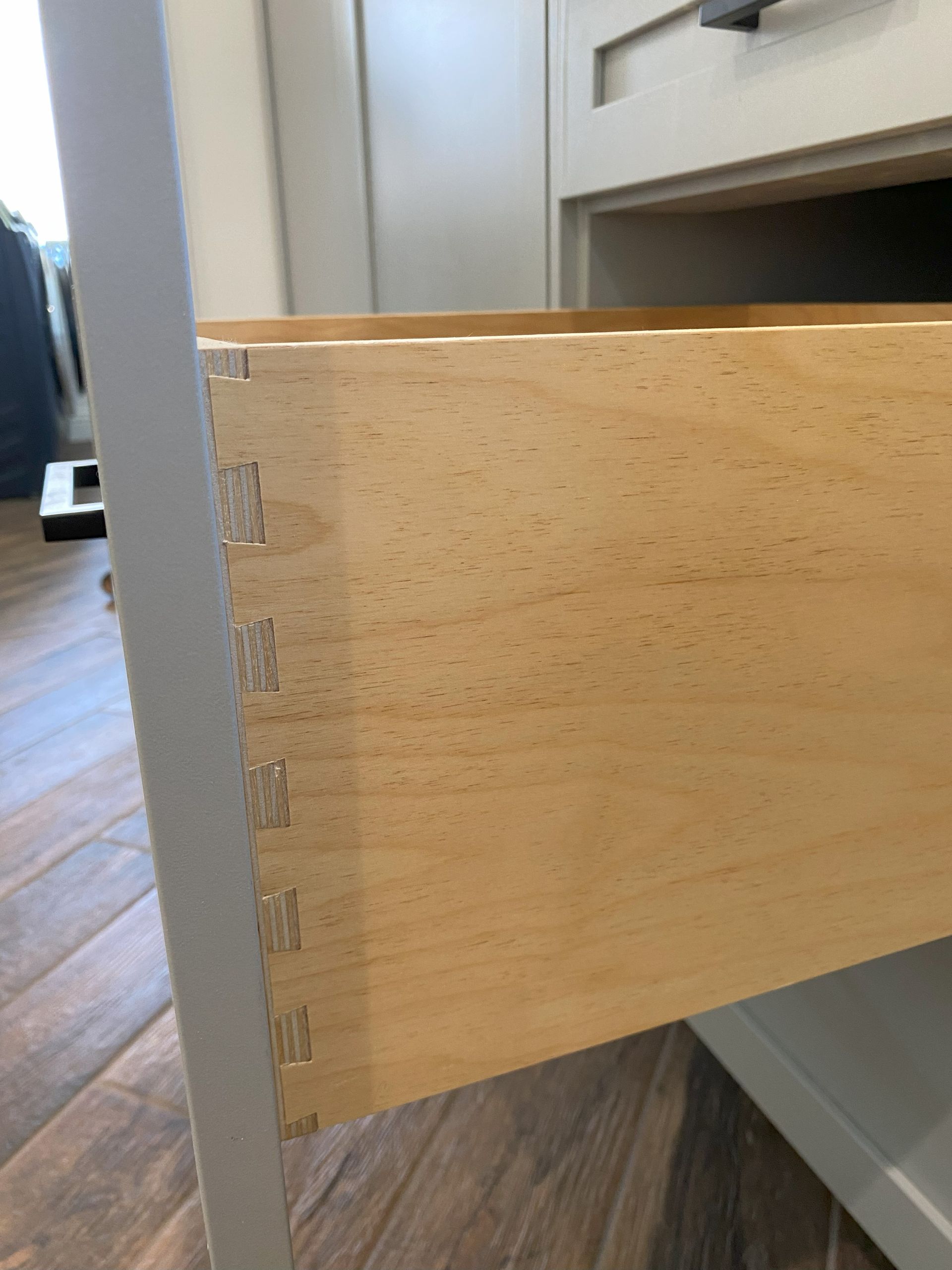 A close up of a wooden drawer on a wooden floor.