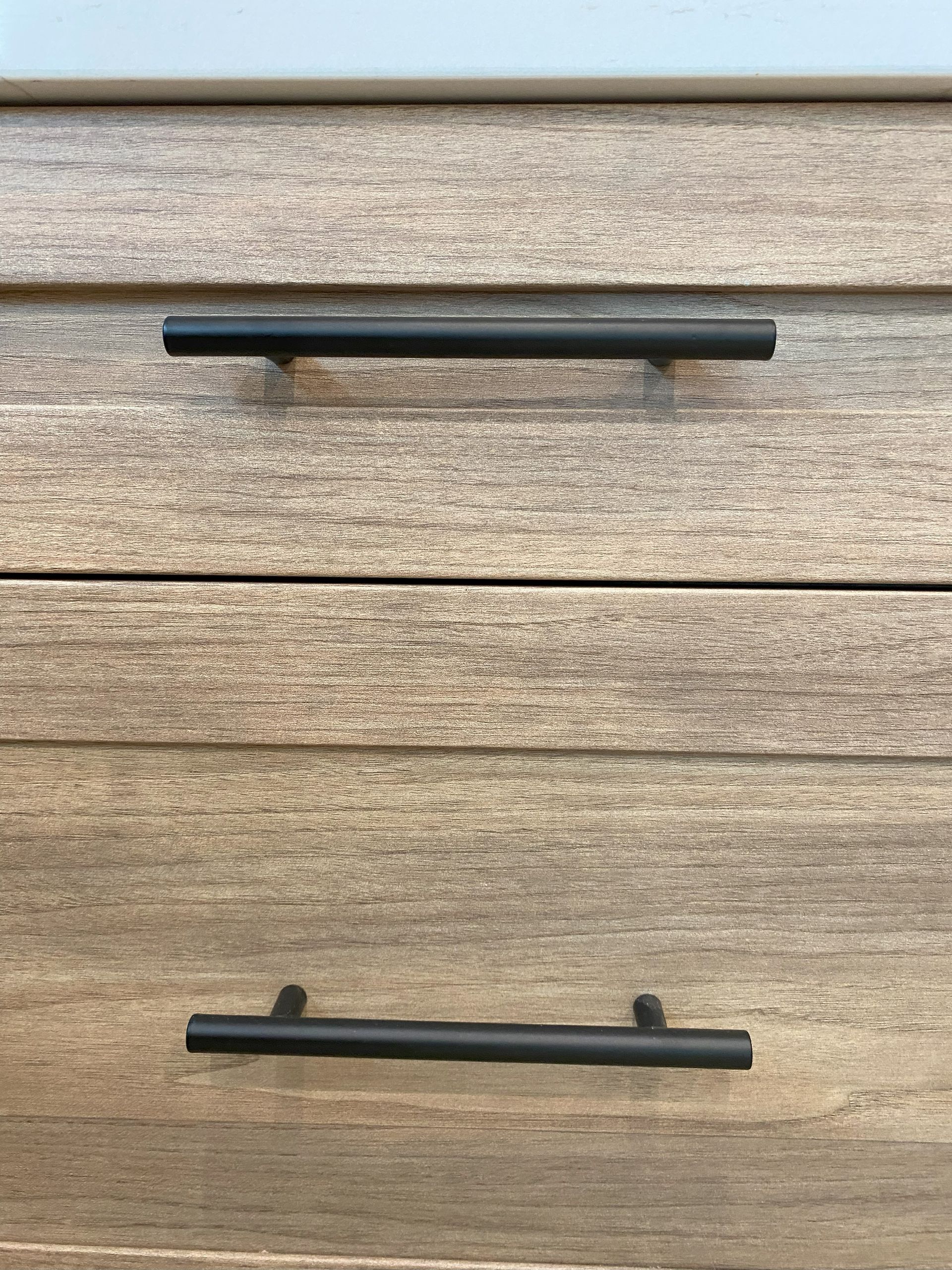 A close up of a wooden dresser with black handles.
