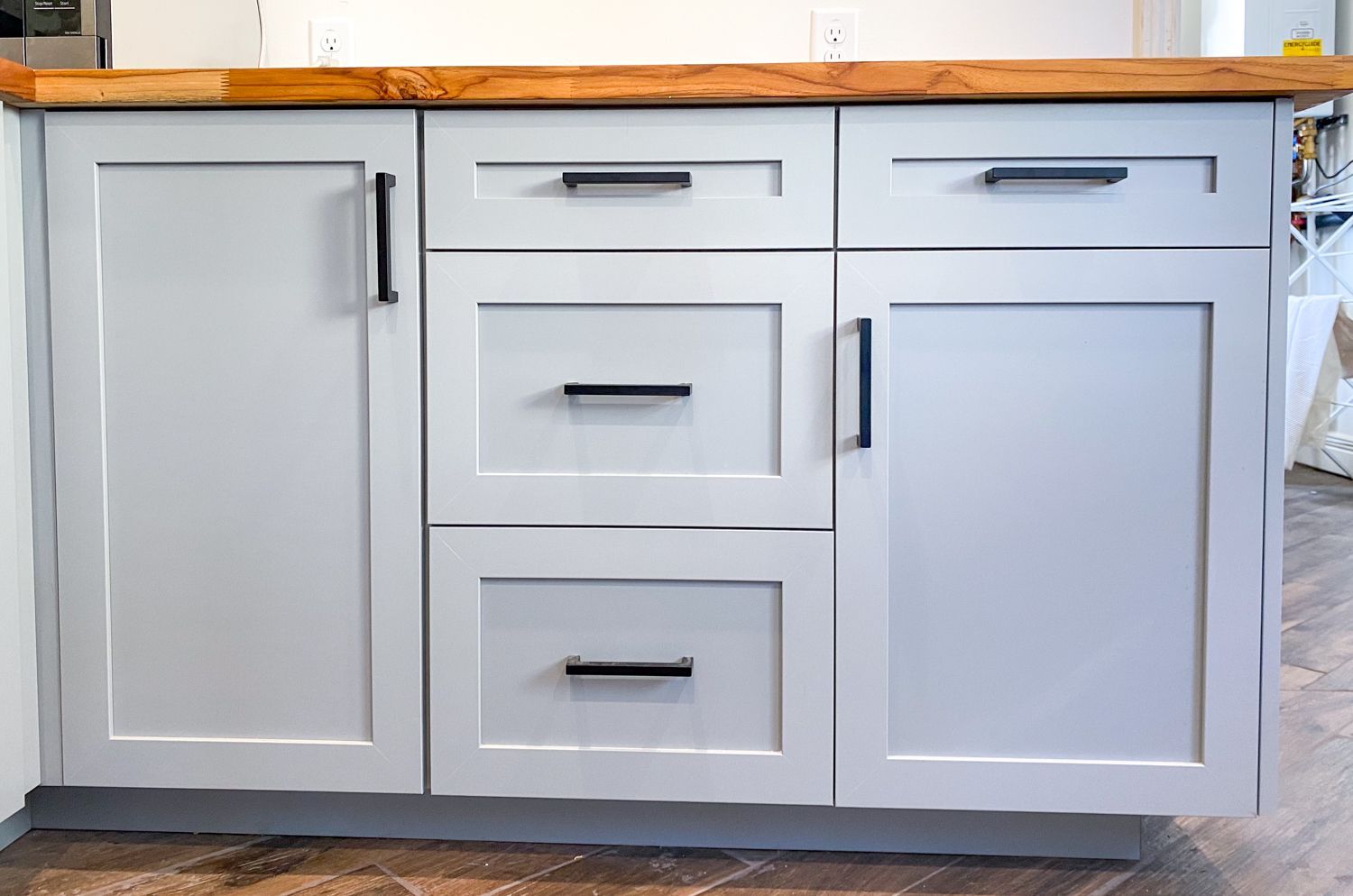 Kitchen cabinets with black handles and a wooden countertop.