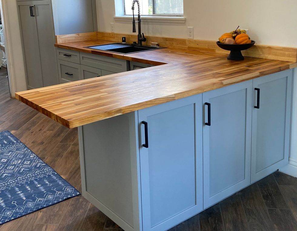 A kitchen with a wooden counter top and blue cabinets.
