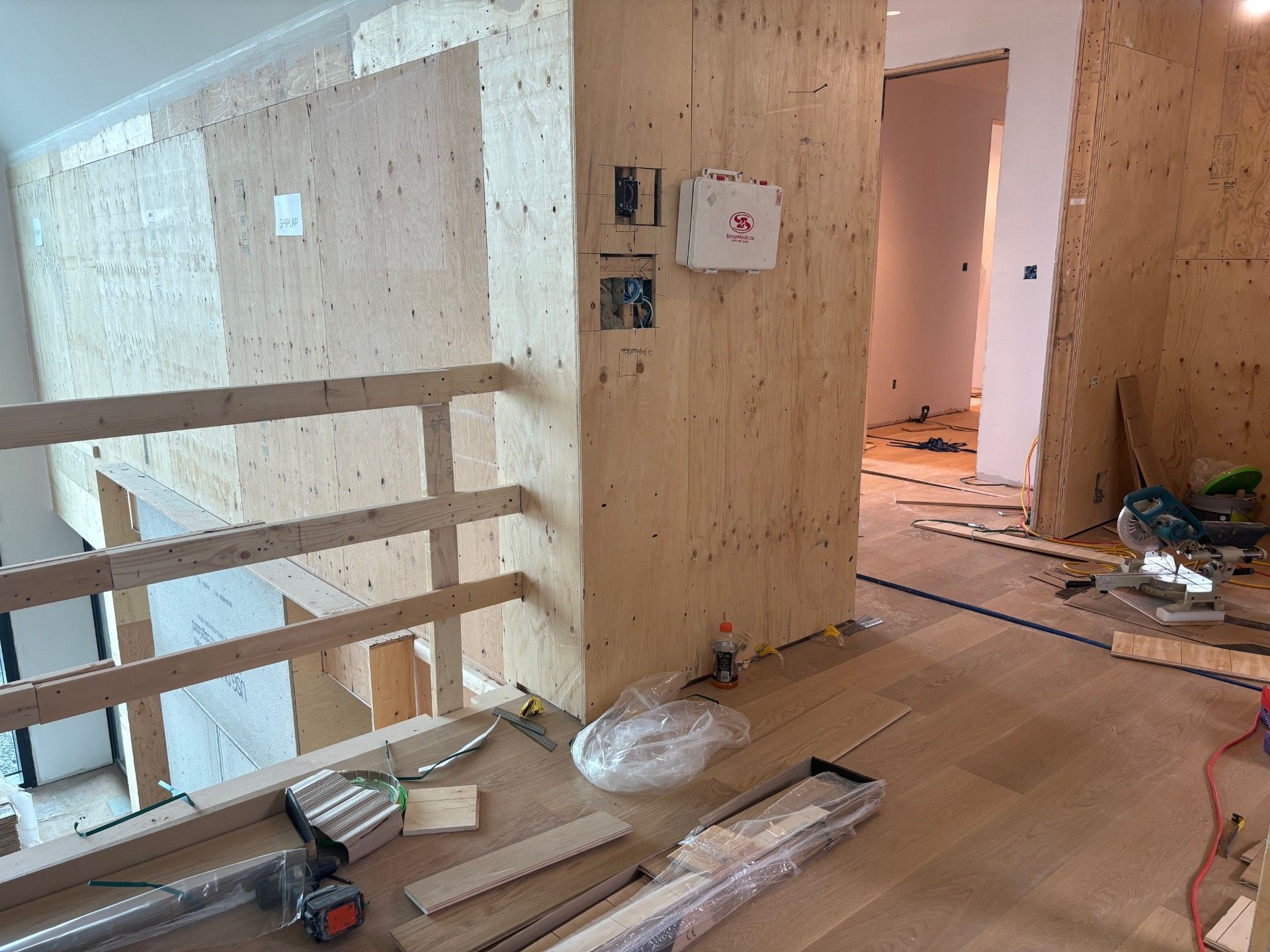Intérieur en cours d'aménagement ; murs en bois, rambarde, outils et porte ouverte.