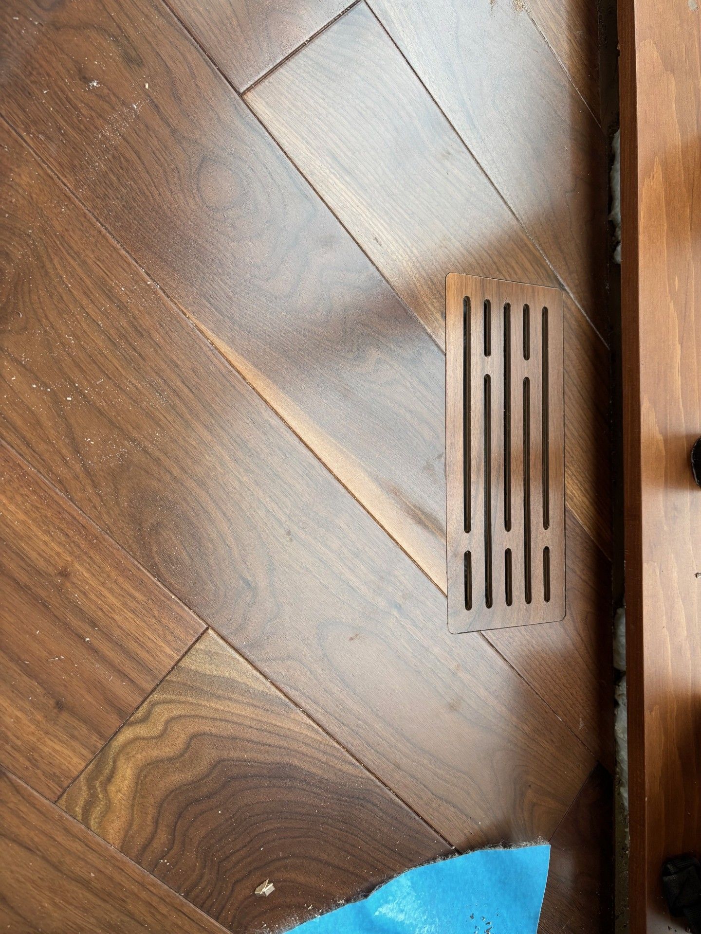Plancher en bois avec une grille d'aération décorative rectangulaire.