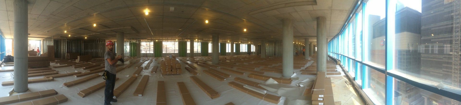 Intérieur d'un bâtiment en construction : colonnes, plafond apparent et parquet.