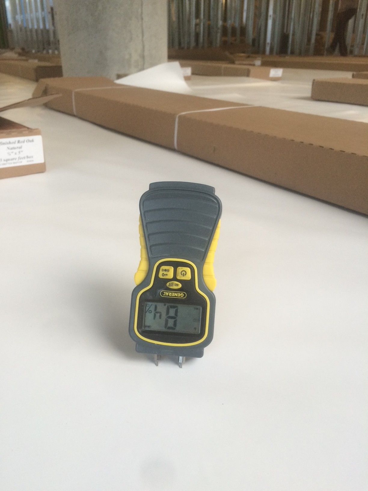 Un humidimètre affichant une valeur de 8,4 est posé sur une surface blanche, sur un chantier de construction.