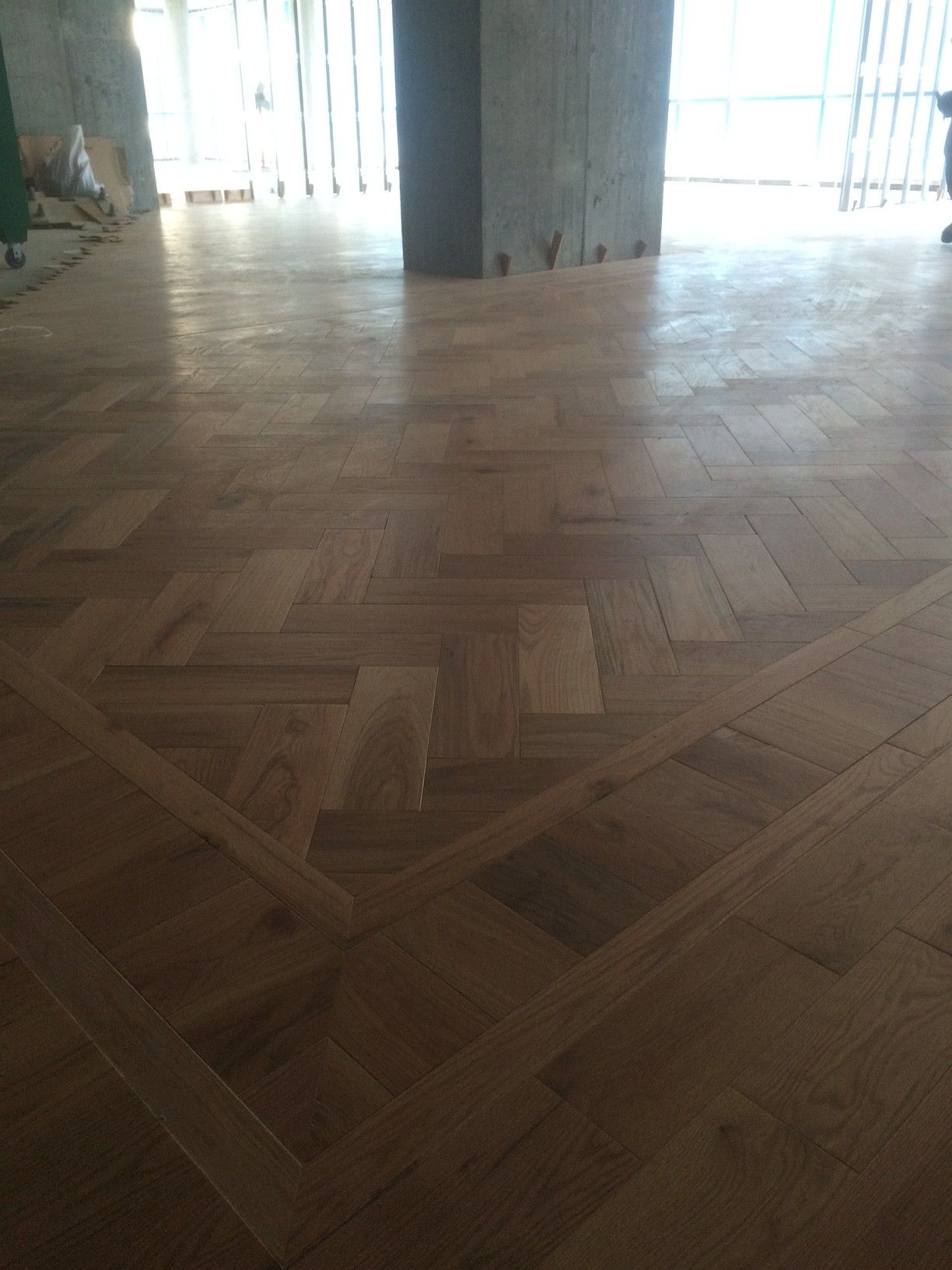 Parquet en bois à motif géométrique dans une pièce avec une grande colonne.